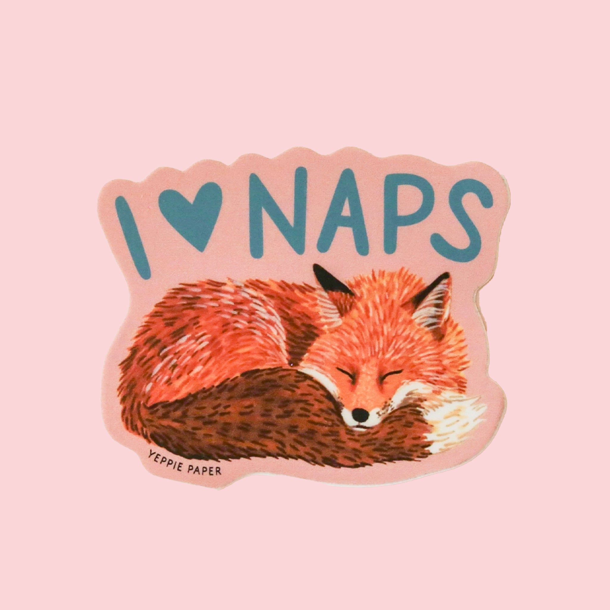 Salmon colored sticker with an illustration of a sleeping fox and turquoise blue text above it that reads, "I heart Naps".