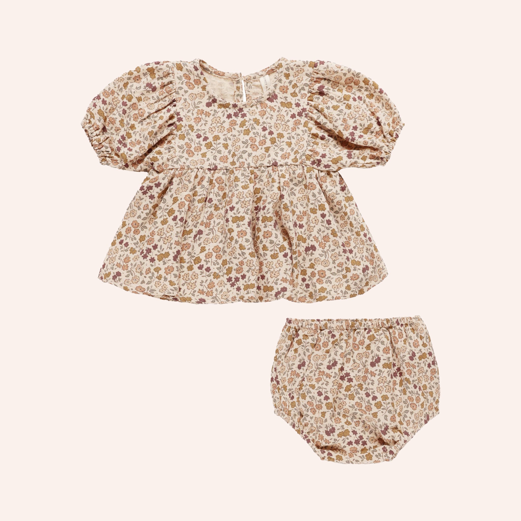 A neutral floral print dress shirt with puff sleeves and matching bloomers for babies. 