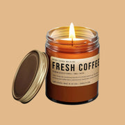 A brown glass jar candle with a brown label that reads, 'Fresh Coffee'.