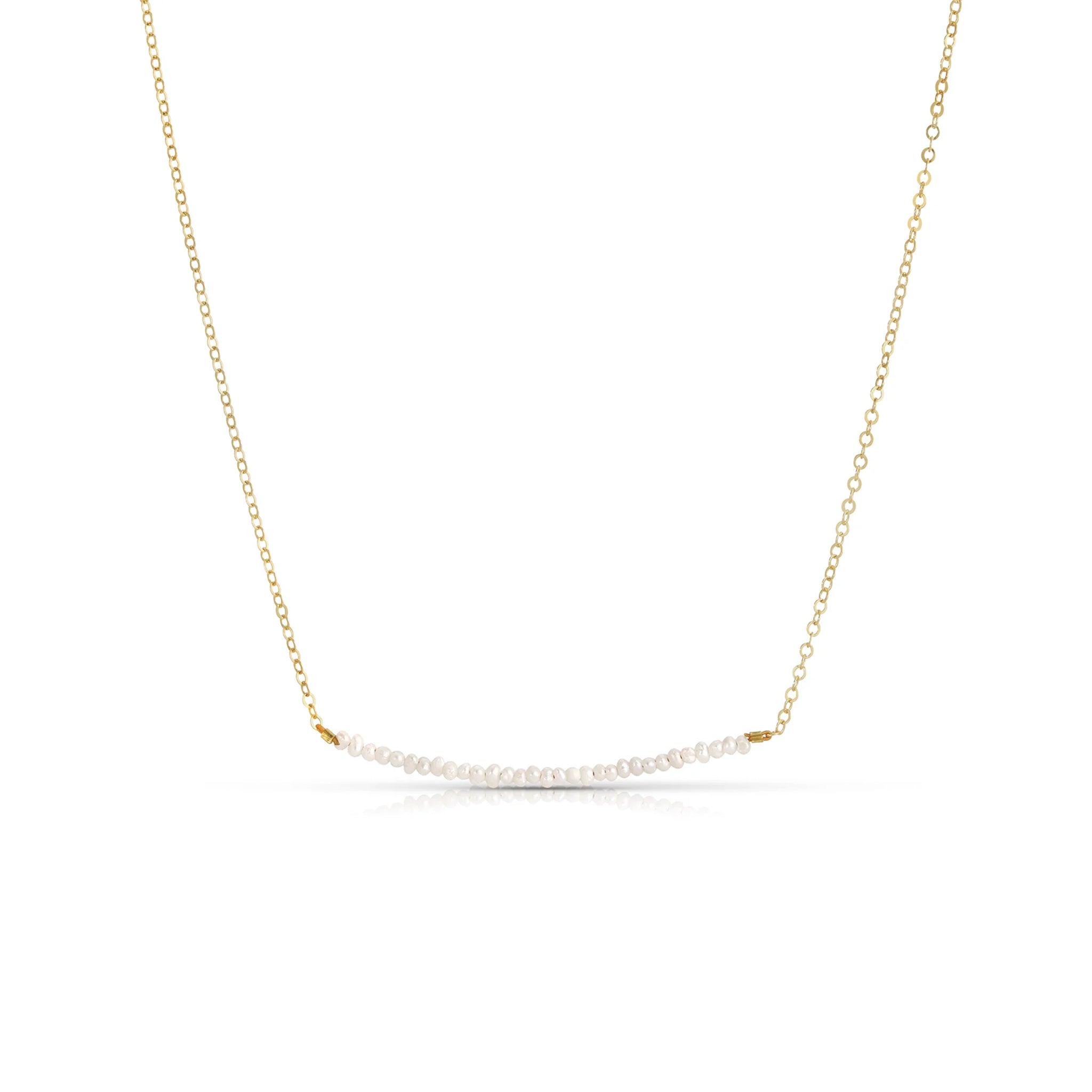 A gold chain necklace with a stack of tiny pearl beads horizontal along the chain. 