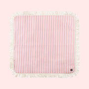 A coral and ivory stripe picnic mat with a fringe edge and a buckle for folding. 