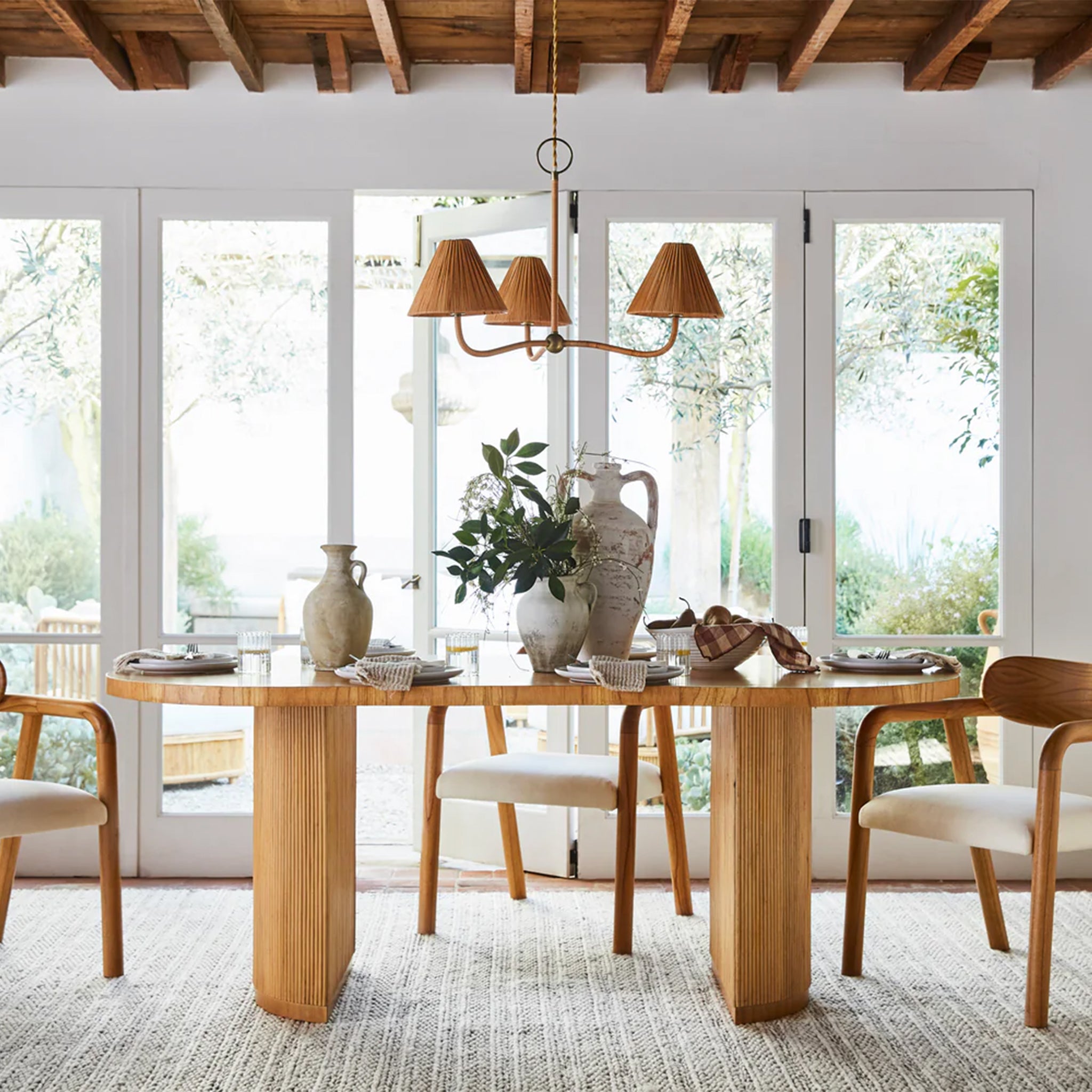 An oval shaped wood dining table with two half moon shaped bases with dowel fluting on the each base.