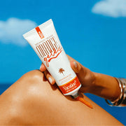 On a blue background is a white squeeze tube with an orange cap and text that reads, "Vacation Brand Orange gelée".