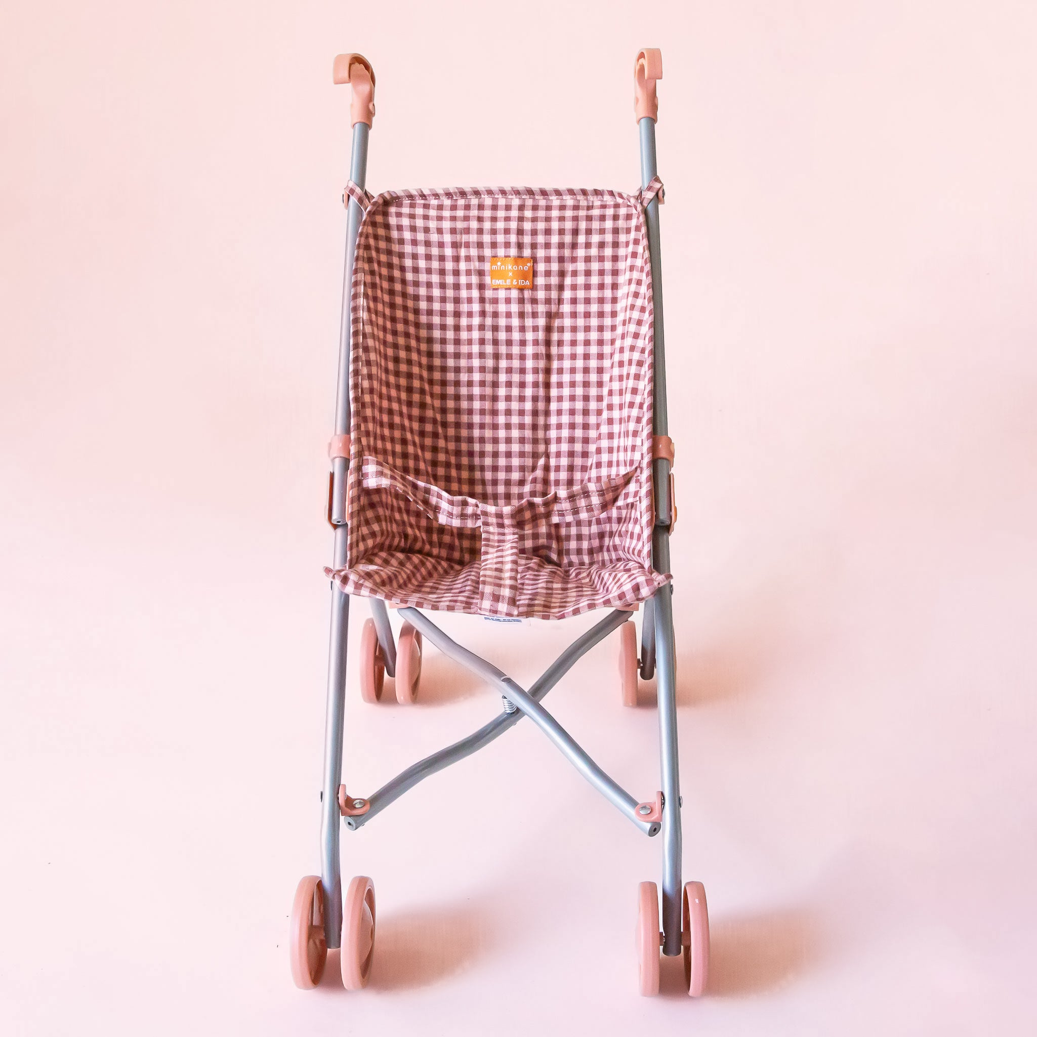 A pink and dark pink gingham printed stroller for dolls with pink wheels. 