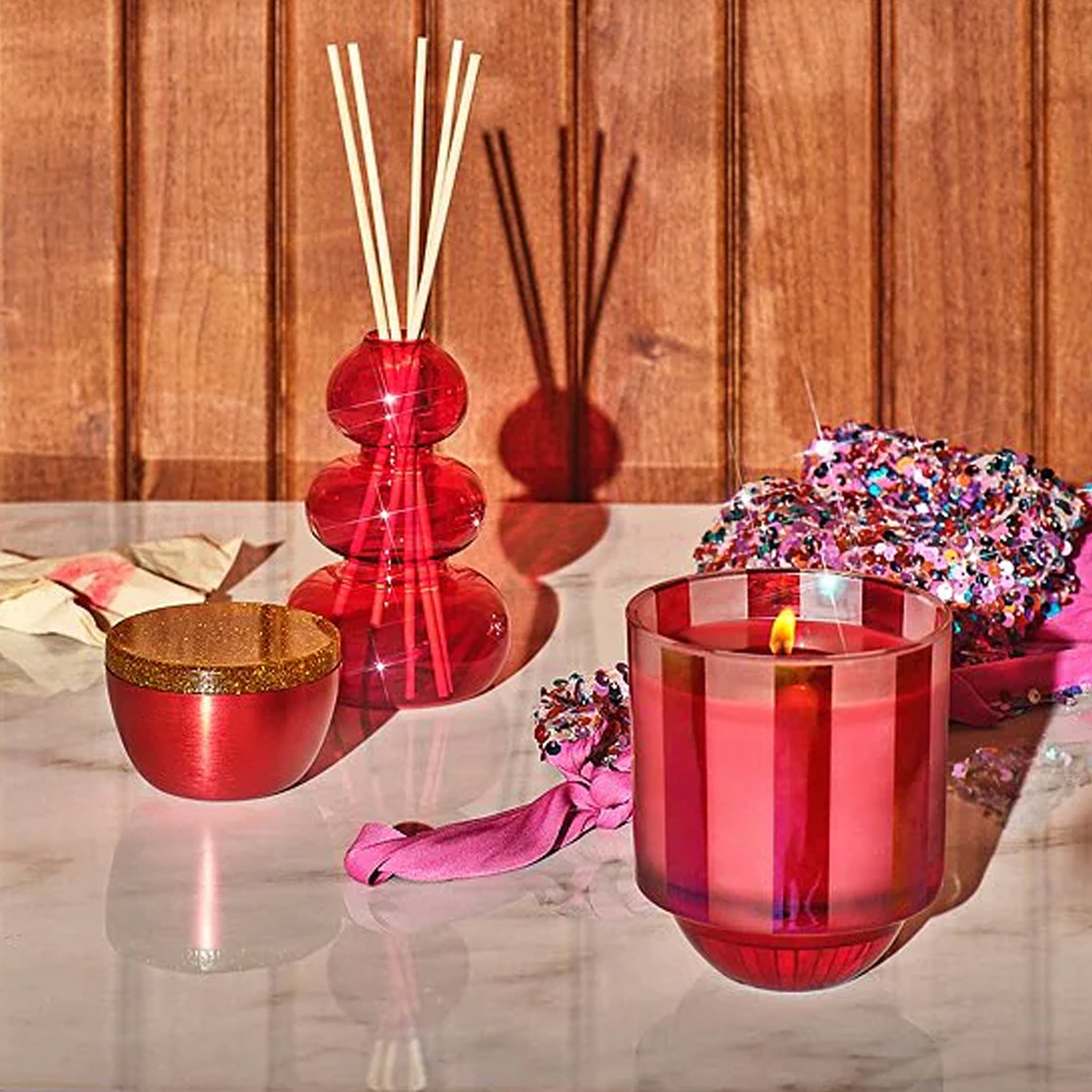 A striped pink and red glass candle in a pink and red box. 