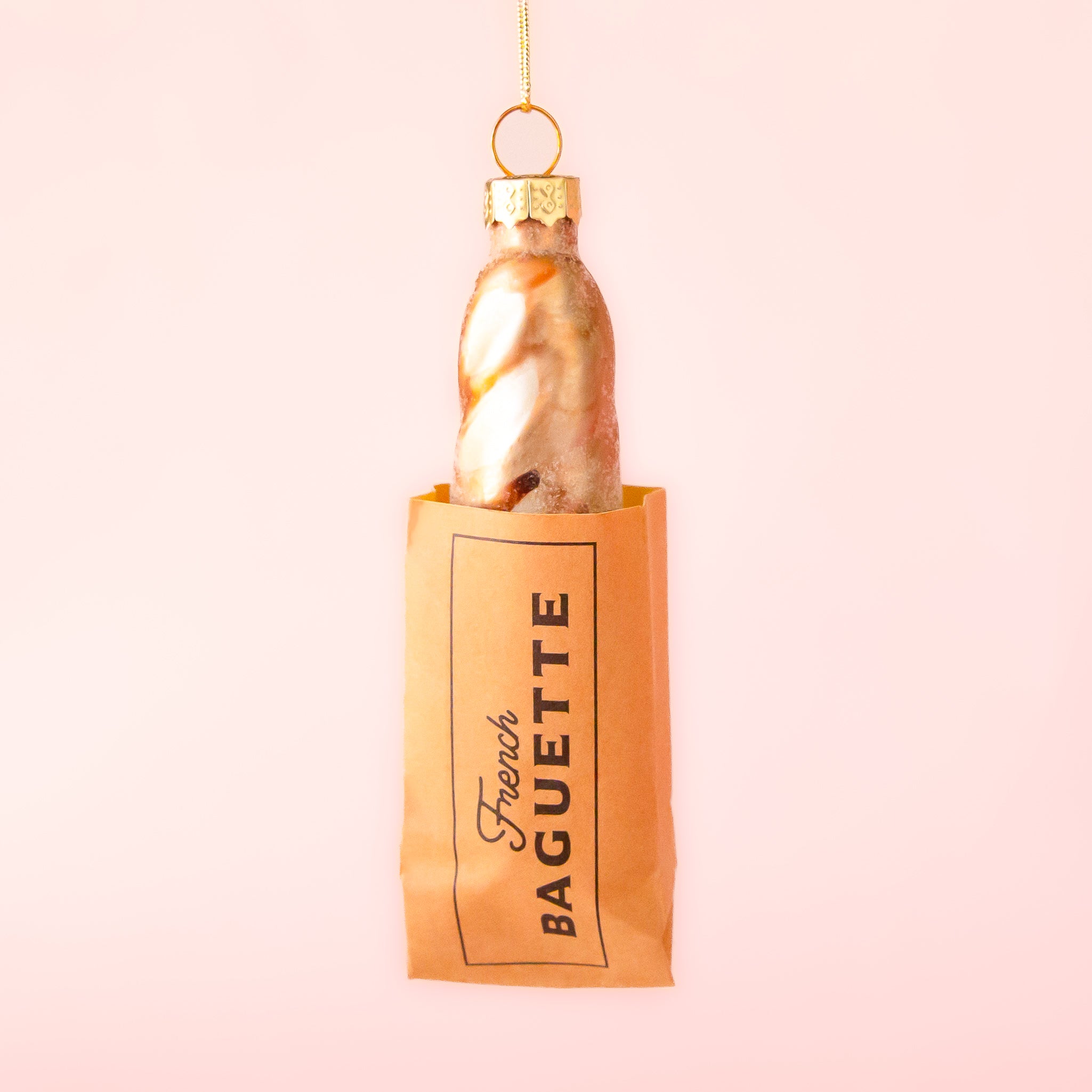 A gold and neutral colored french baguette shaped glass ornament with glitter details. 