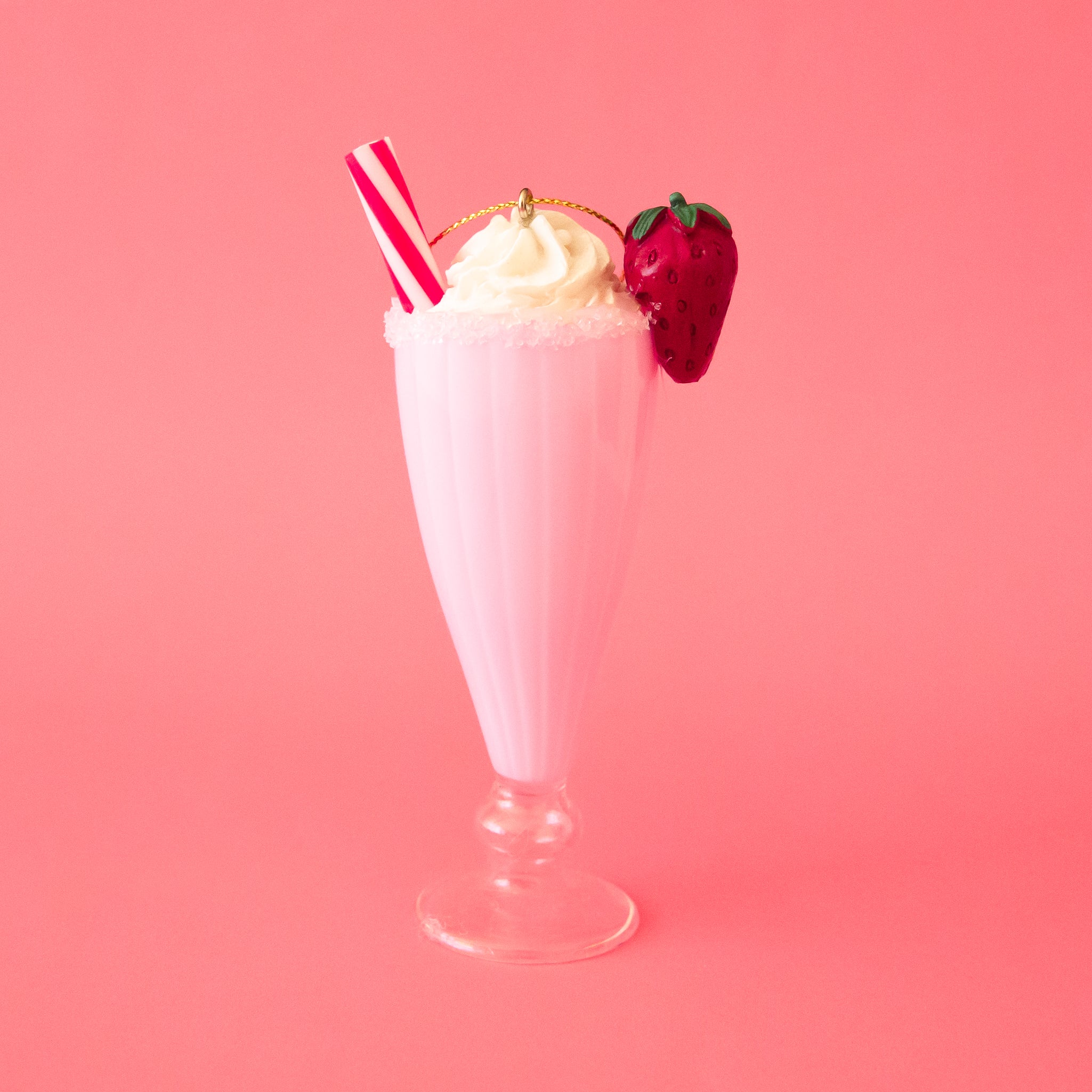 A pink milkshake shaped ornament with a red and white straw and a red strawberry garnish. 