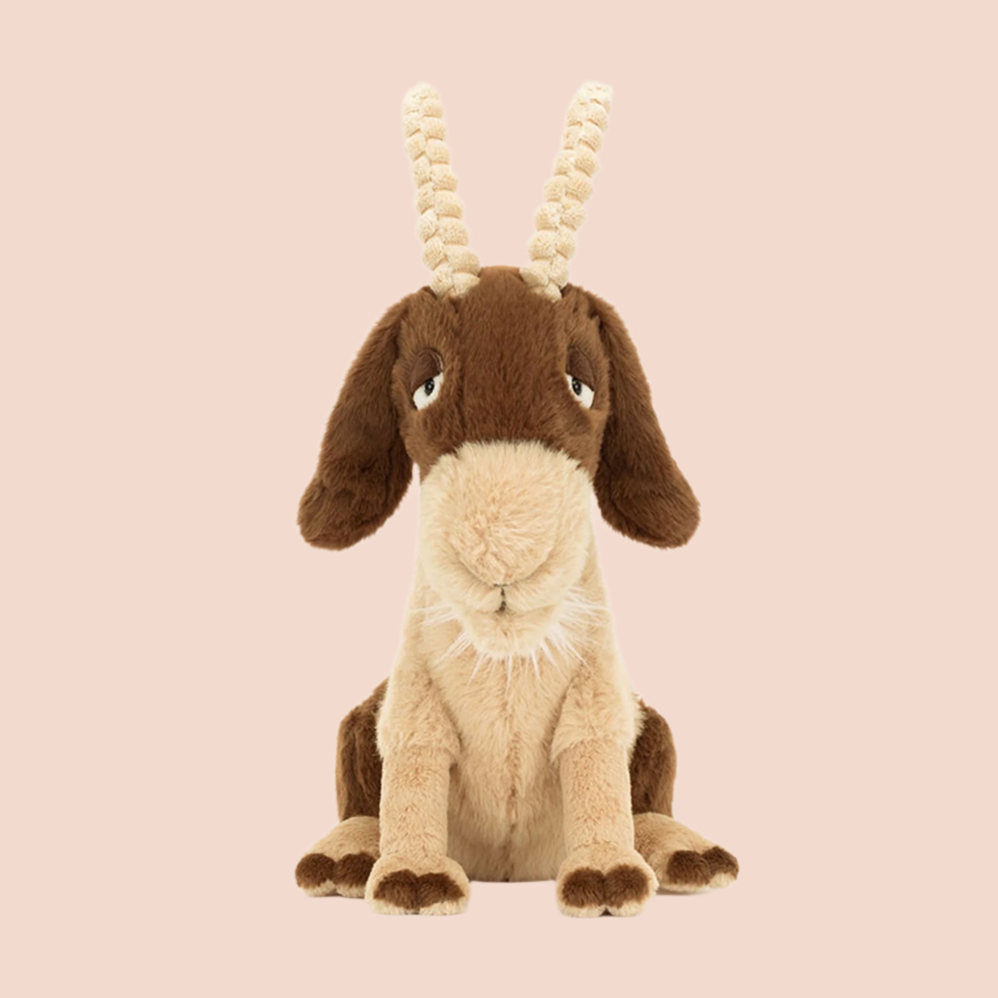 A brown and tan goat shaped stuffed animal with sleepy eyes, floppy ears and two soft horns. 