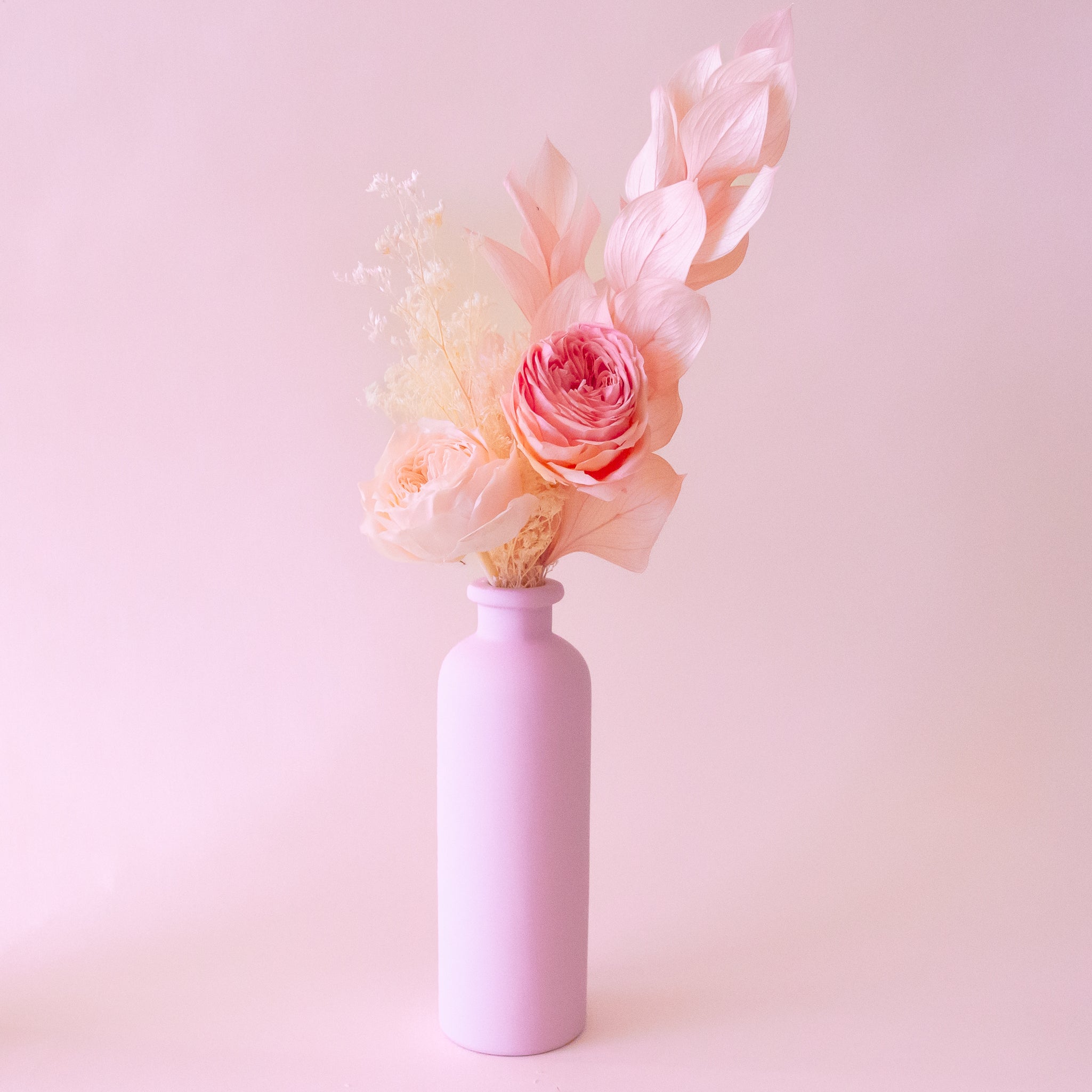 The light pink vase with a dried floral arrangement. 