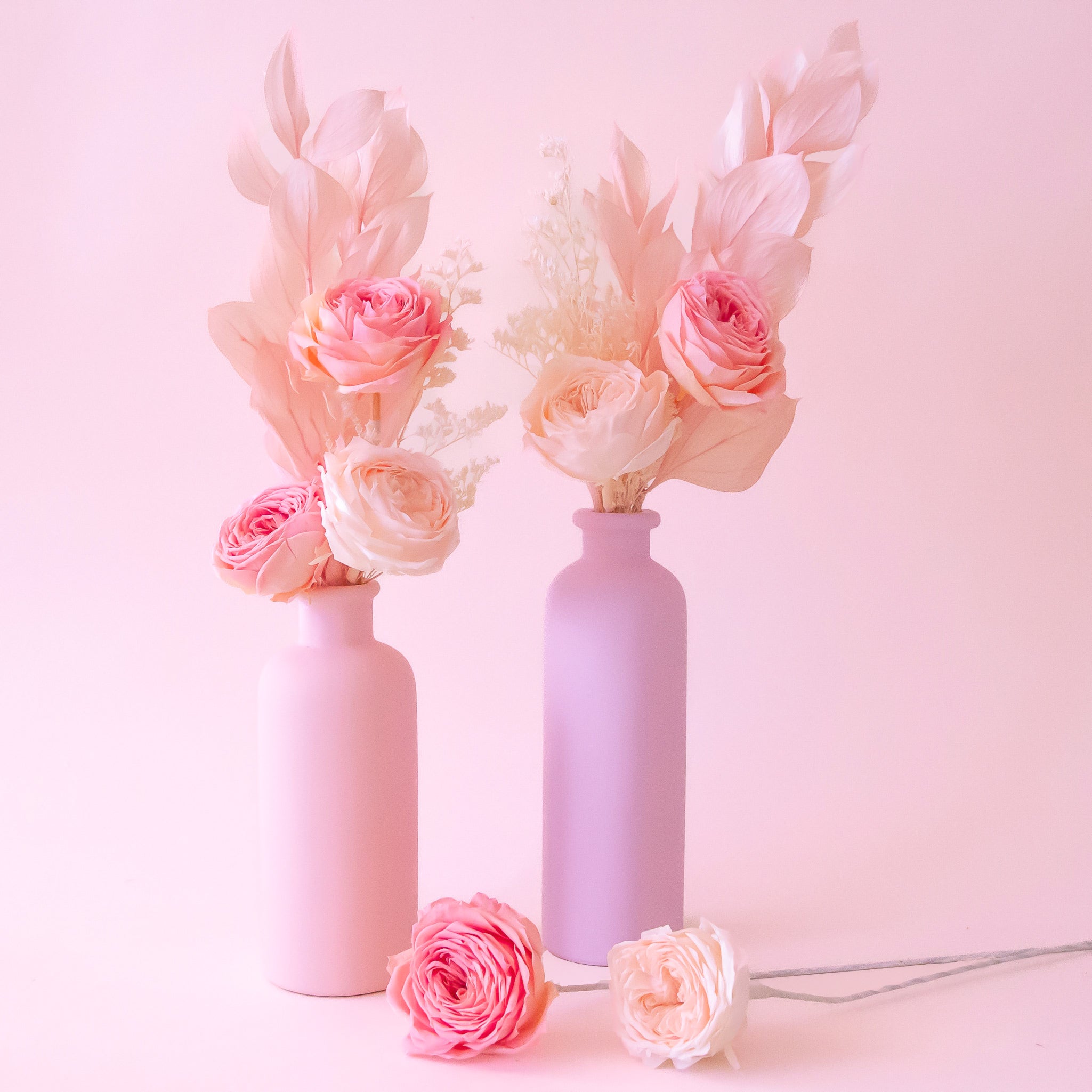 A peach colored bud vase with dried florals inside. 