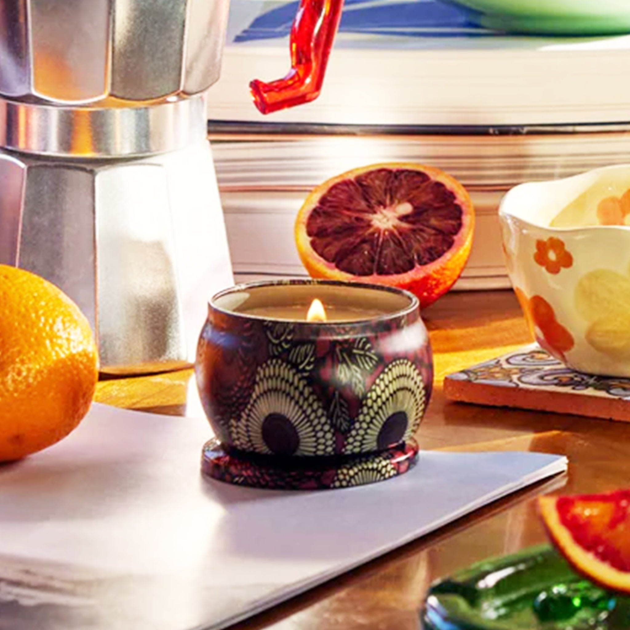 A red tin with a single wick candle inside and a label on the lid that reads, "Voluspa Goji Torocco Orange".