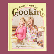 A yellow bookcover with a photo of Dolly Parton and her sister on the cover with text that reads, 'Good Lookin' Cookin' A Year of Meals'.