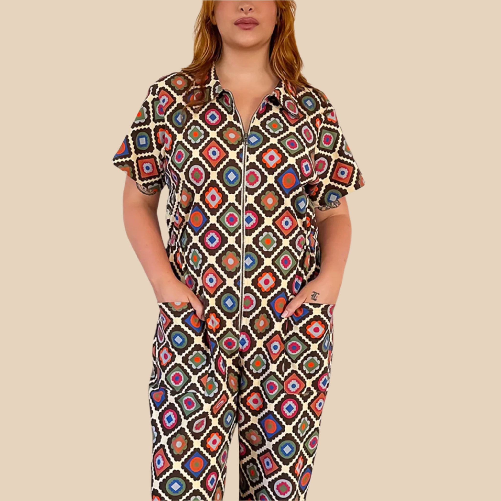 A multi-colored short sleeve jumpsuit with a zipper up the front and a floral pattern. 