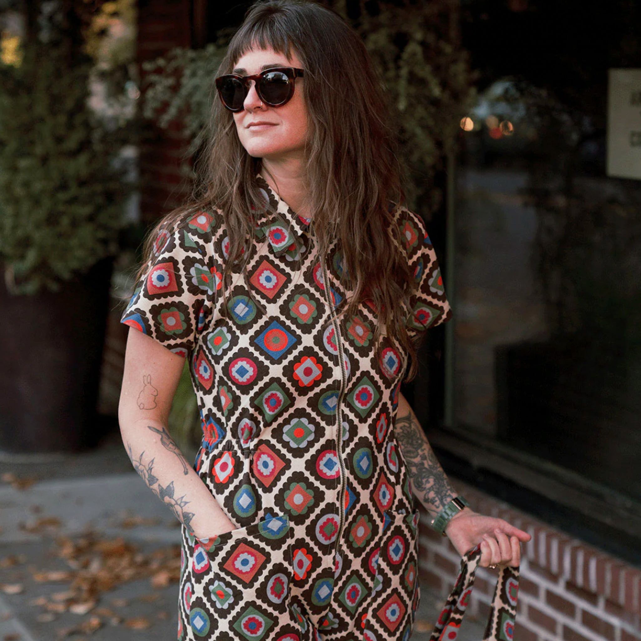 A multi-colored short sleeve jumpsuit with a zipper up the front and a floral pattern. 