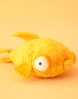 On a yellow background is a yellow stuffed toy fish with puffy eyes and lips.