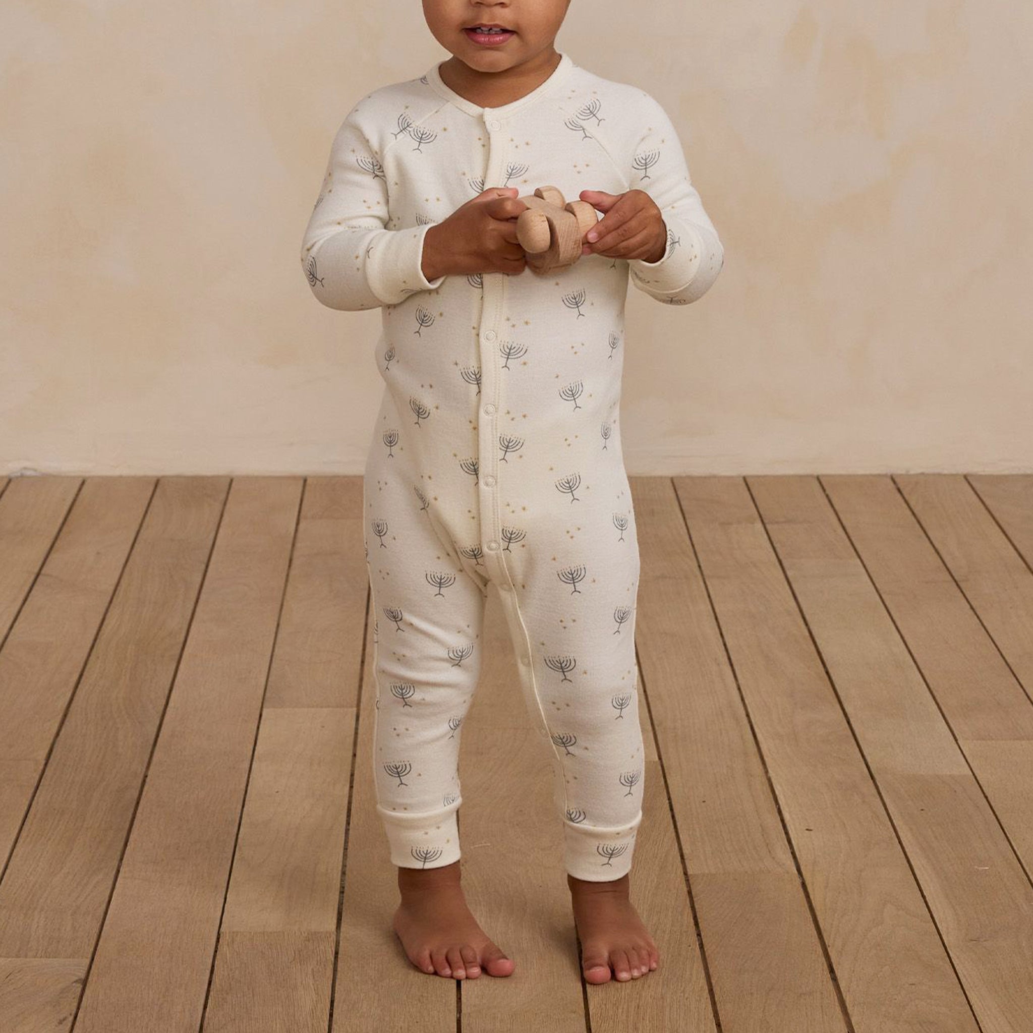 A cream colored long john pajamas with a menorah Hanukkah print. 