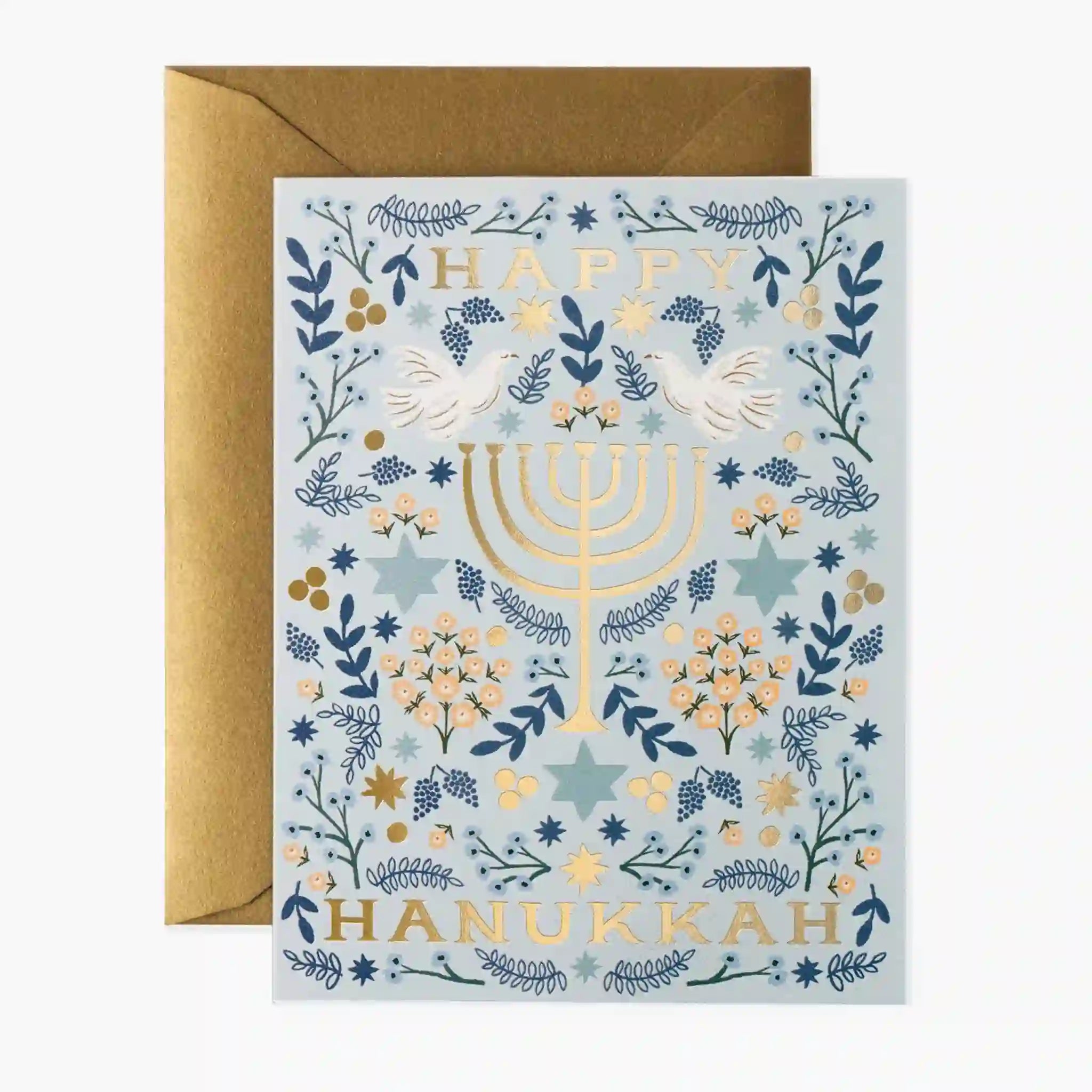 On a neutral background is a blue and white greeting card with gold fold text that reads, &quot;Happy Hanukkah&quot; along with a menorah graphic. 