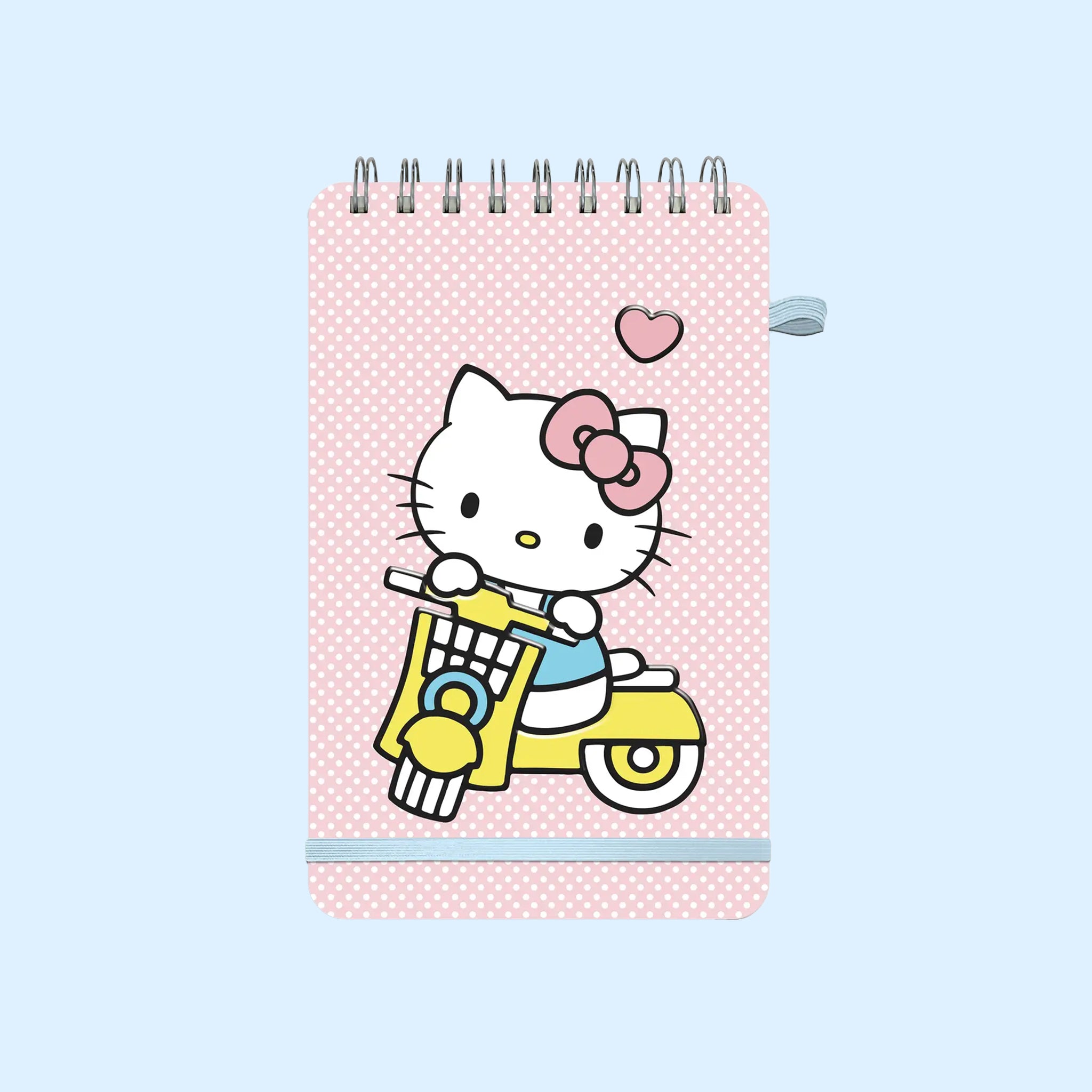 A light pink spiral bound notebook with a graphic of Hello Kitty on a yellow scooter. 