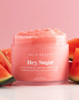 On a pink background is a jar of pink sugar scrub with white text that reads, "Hey, Sugar Exfoliating All Natural Body Scrub". 