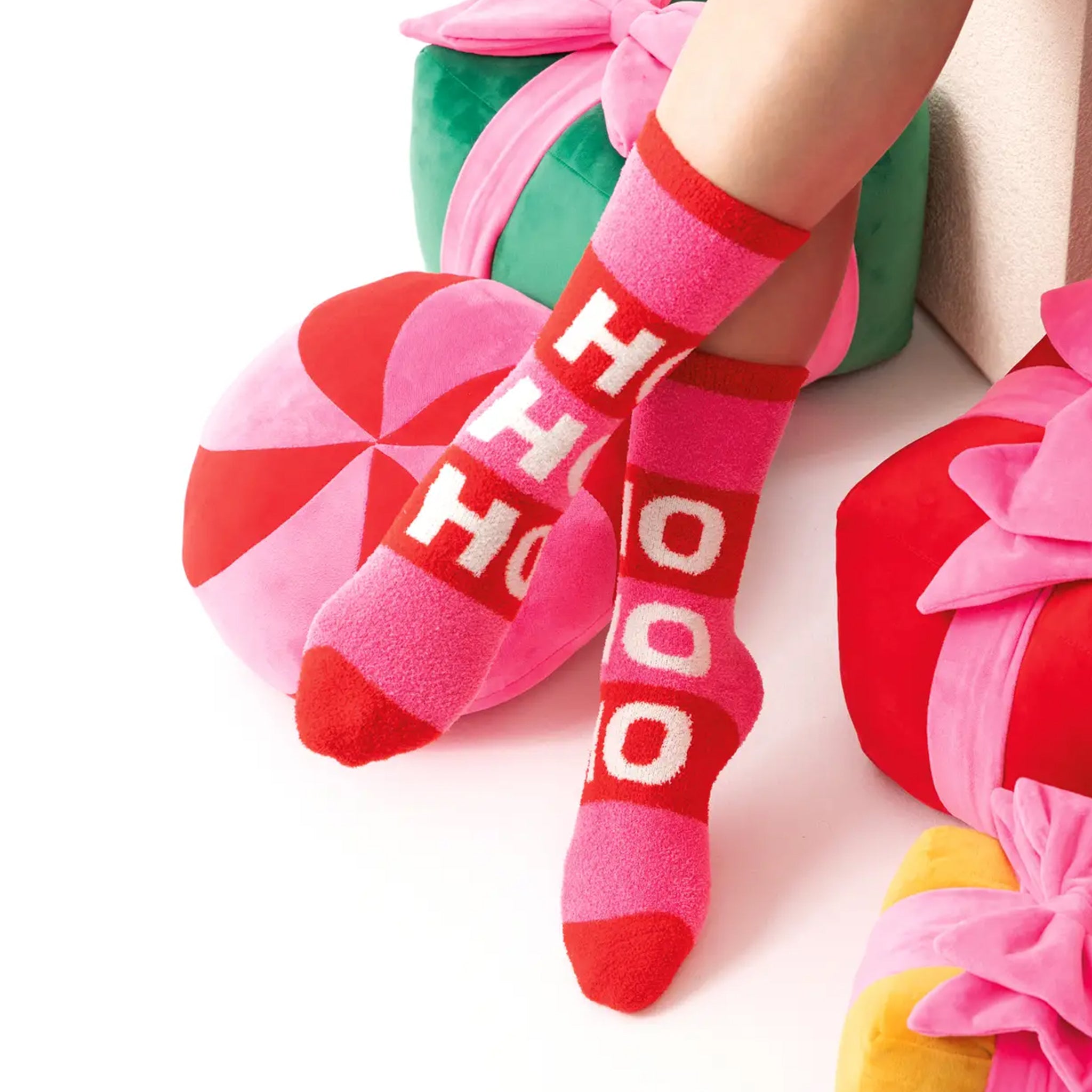 A pair of pink and red fuzzy socks that read, &#39;Ho Ho Ho&#39; in white text down the front. 