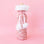 On a pink background is a pink sequin wine gift bag with fuzzy white details and a pom pom pink bow. 