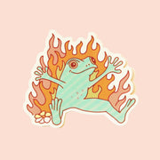 On a cream background is a sticker of a green frog with flames around it.