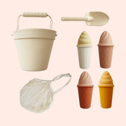 A beach play toy set with a bucket, a shovel, a bag, and four ice cream shape molds. 