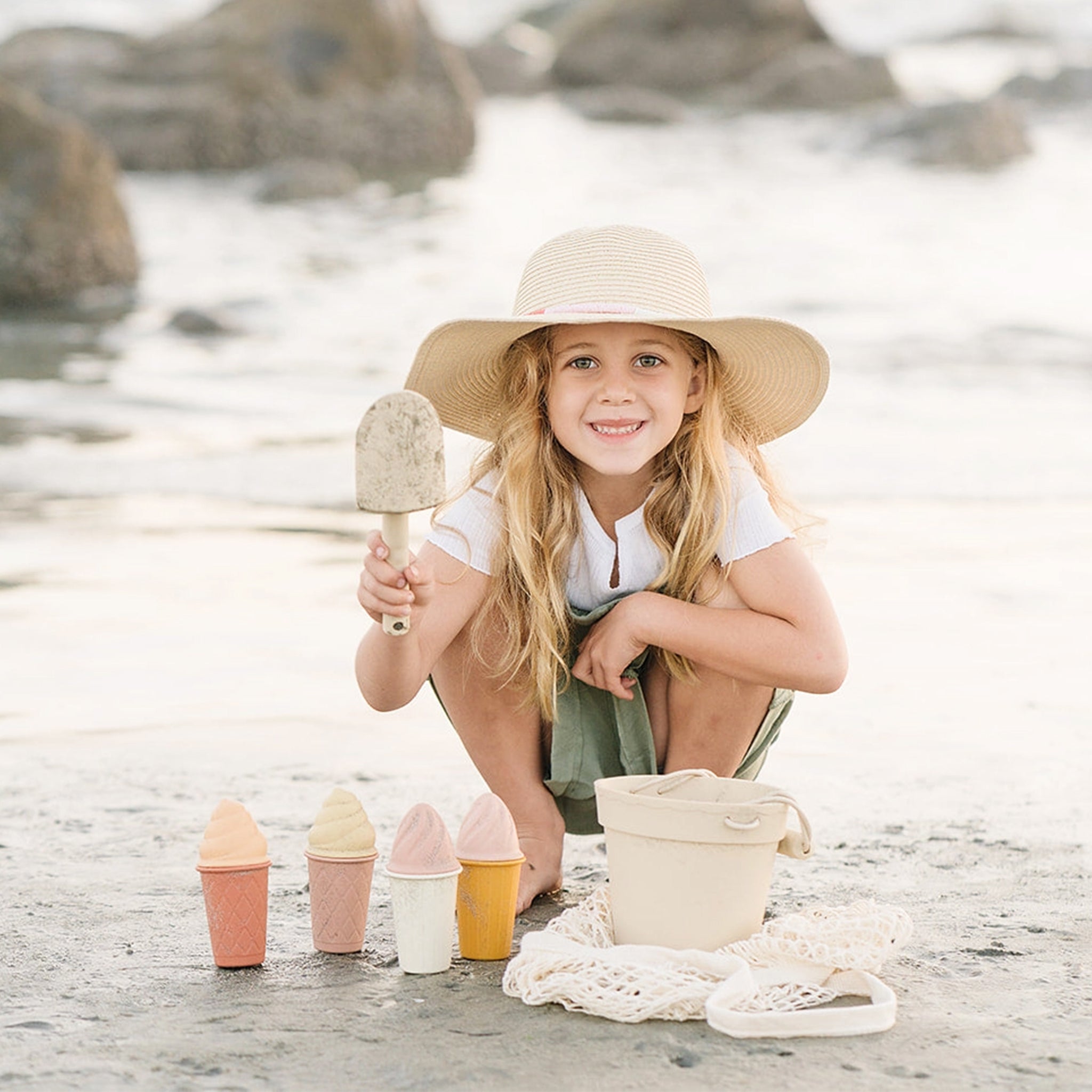 A beach play toy set with a bucket, a shovel, a bag, and four ice cream shape molds.