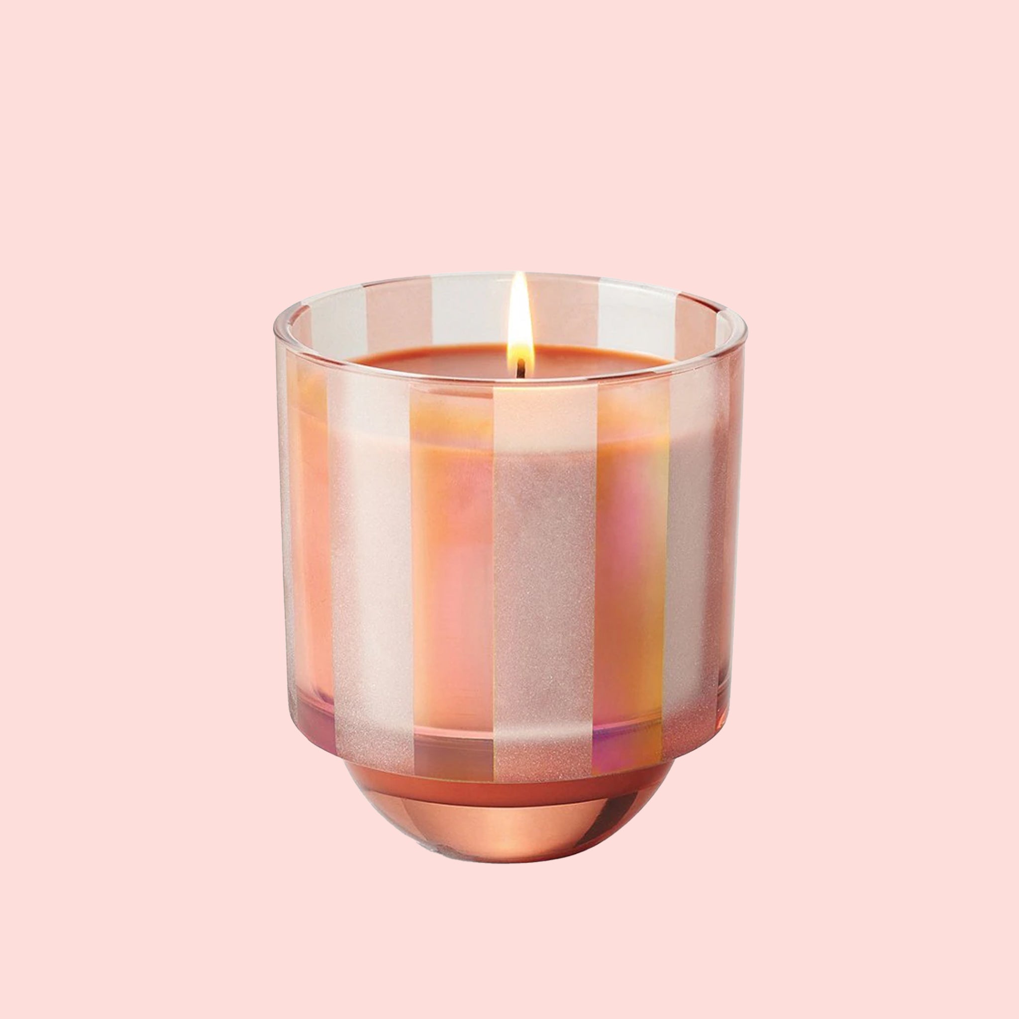 A light pink and orange striped glass jar candle. 