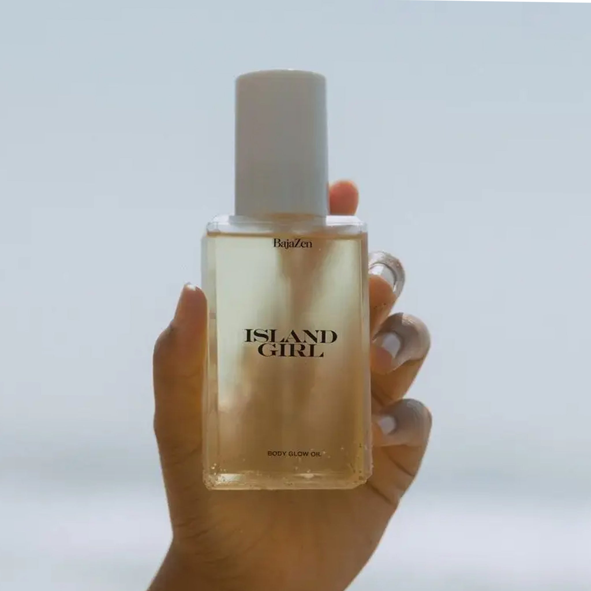 A clear container of body glow oil with a white pump lid and black text that reads, "Island Girl".