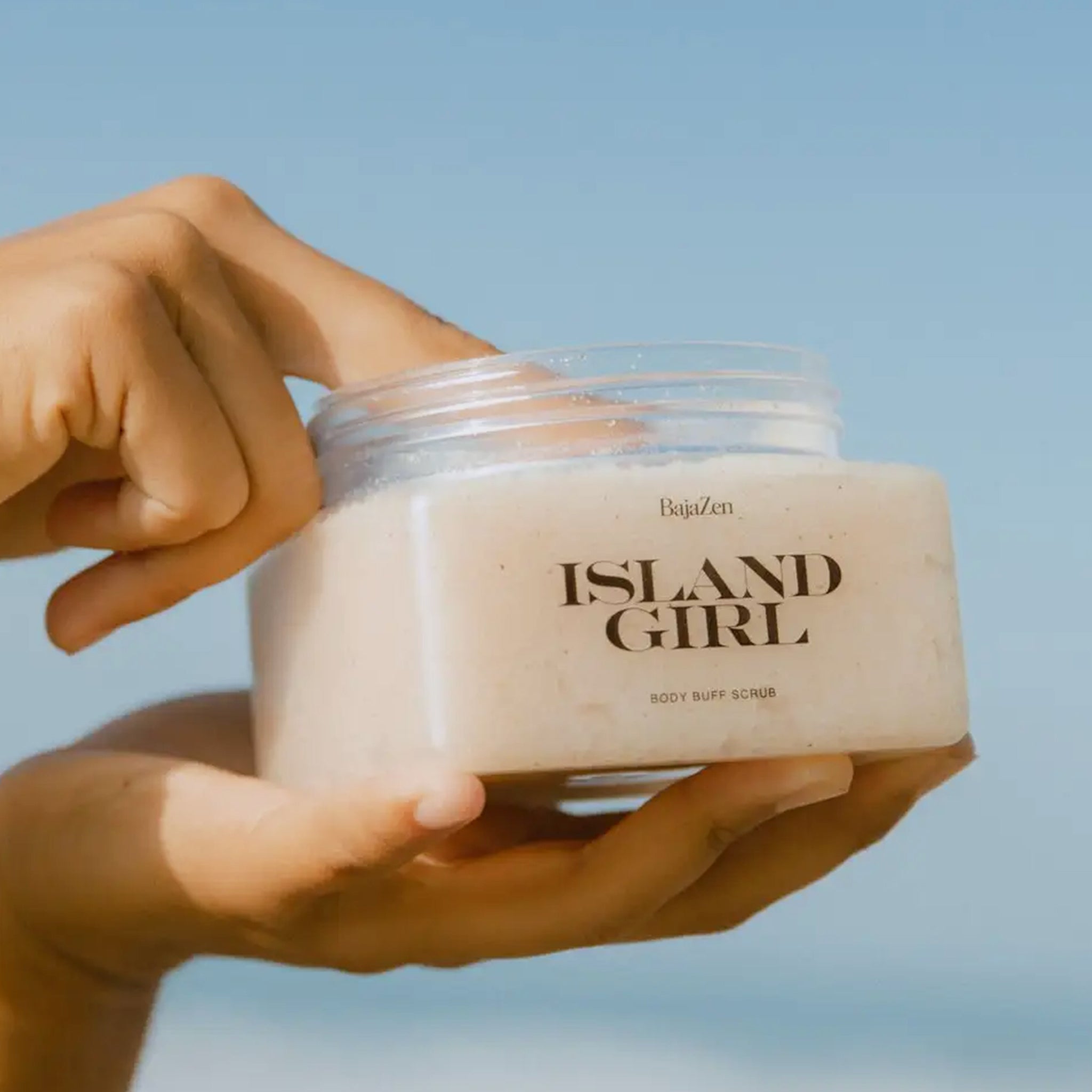 A clear container with a neutral body scrub, white lid and text that reads, "Island Girl". 