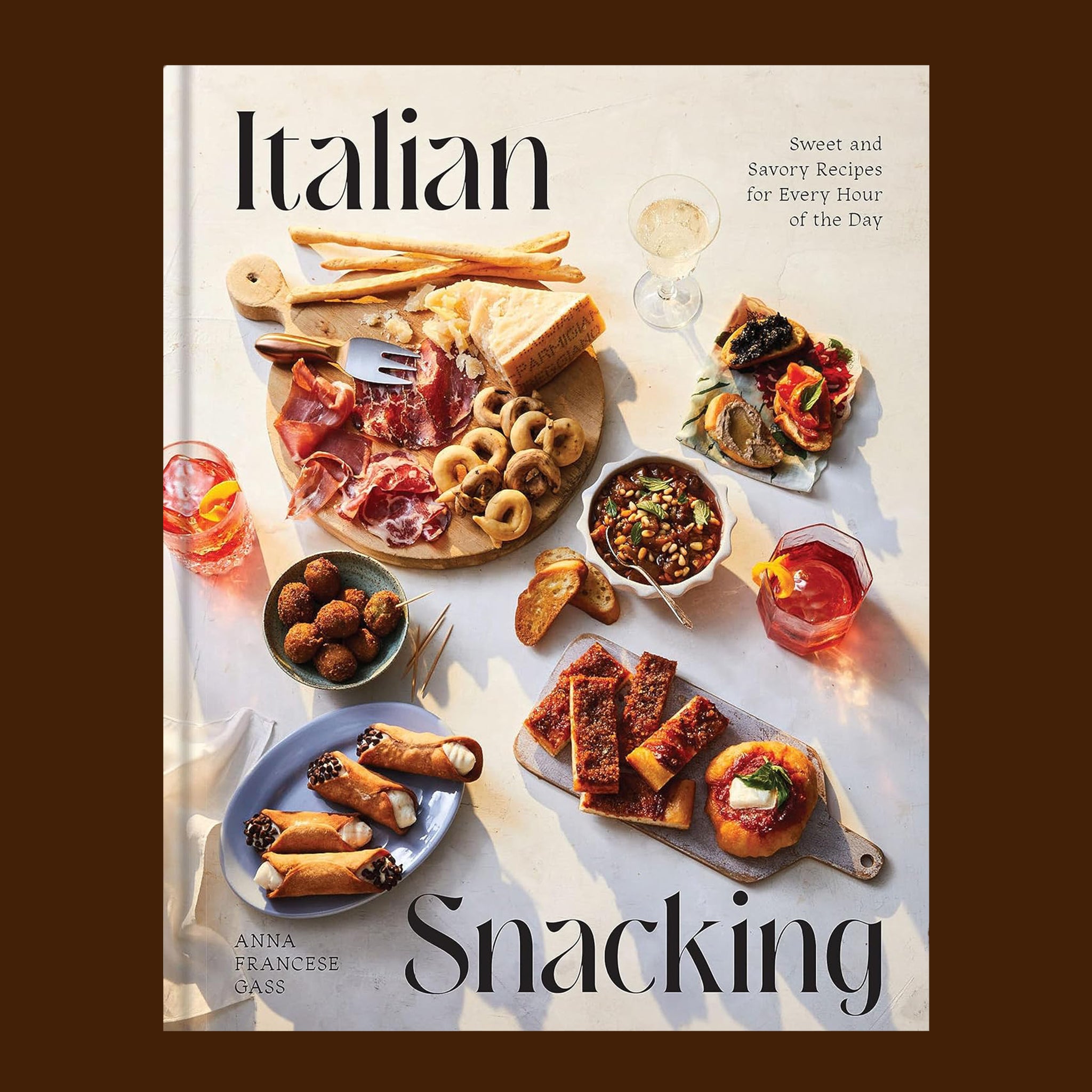 A neutral book cover with a spread of Italian small bites and black text that reads, "Italian Snacking'. 