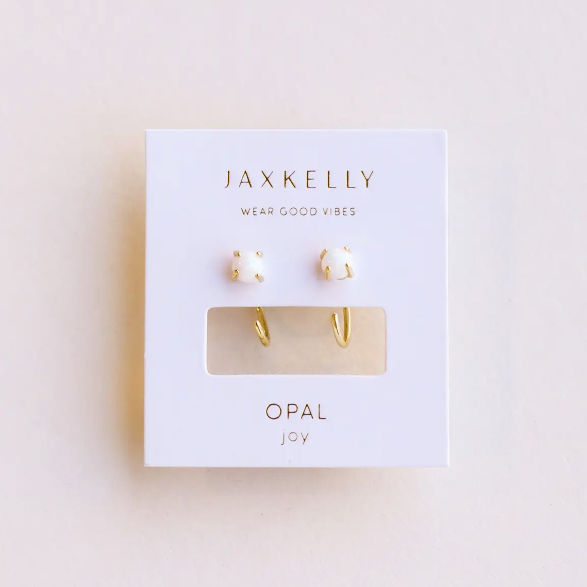 A pair of huggie hoop earrings with a small white opal stud. 