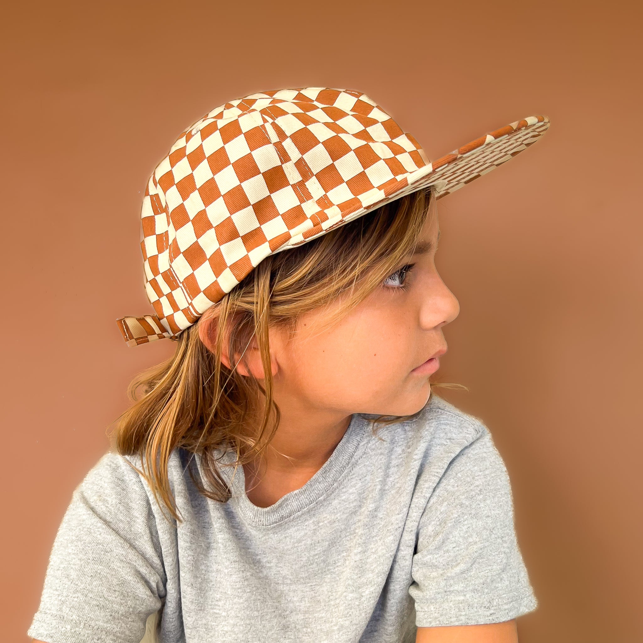 A rust and ivory checker pattern baseball hat for kids. 