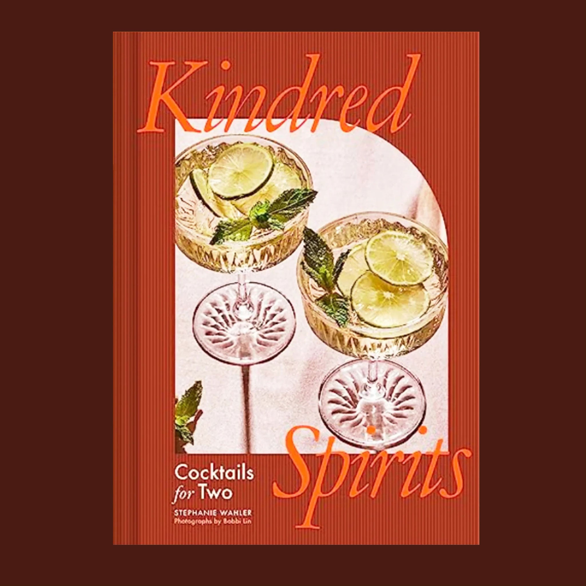 A burnt reddish orange book cover with a photograph of two beverages in coupe glasses and the title that reads, "Kindred Spirits".