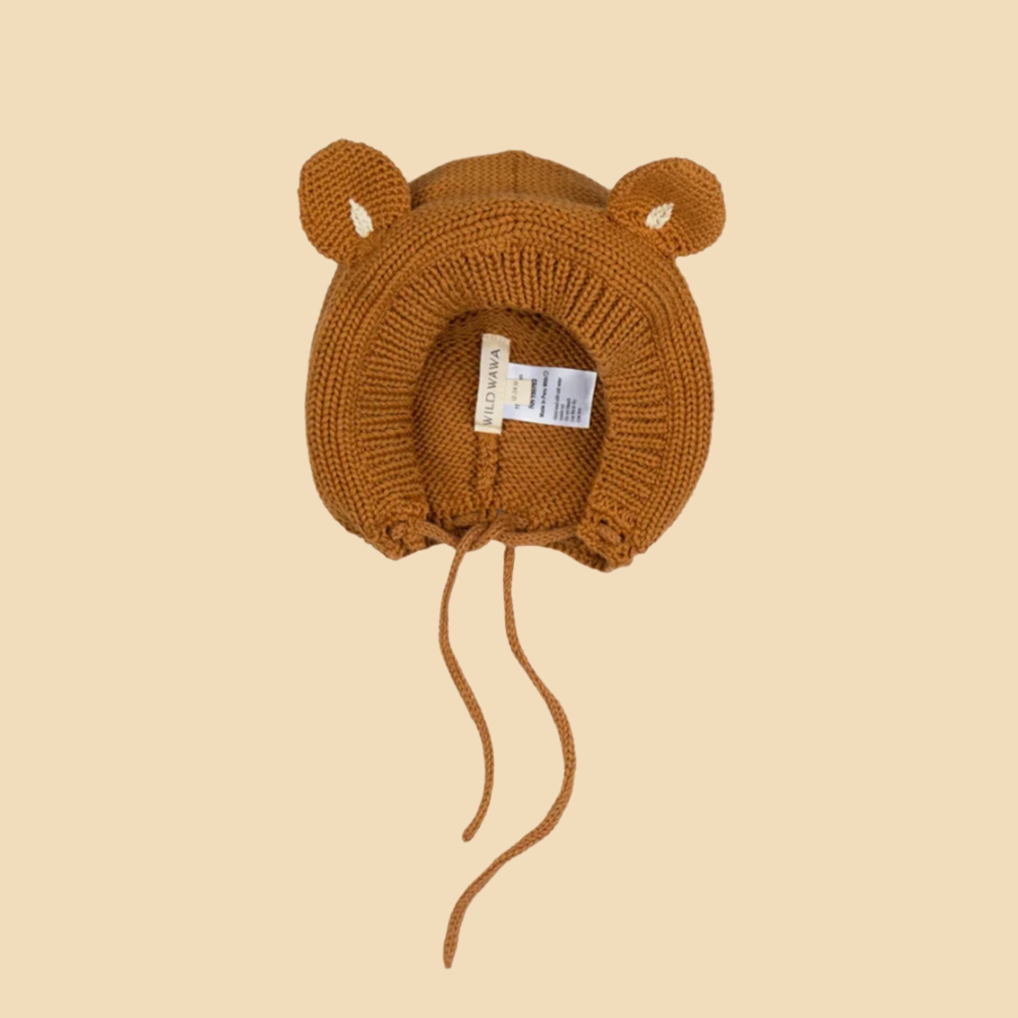 A warm brown bear shaped knitted bonnet with a neck strap. 