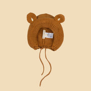 A warm brown bear shaped knitted bonnet with a neck strap. 