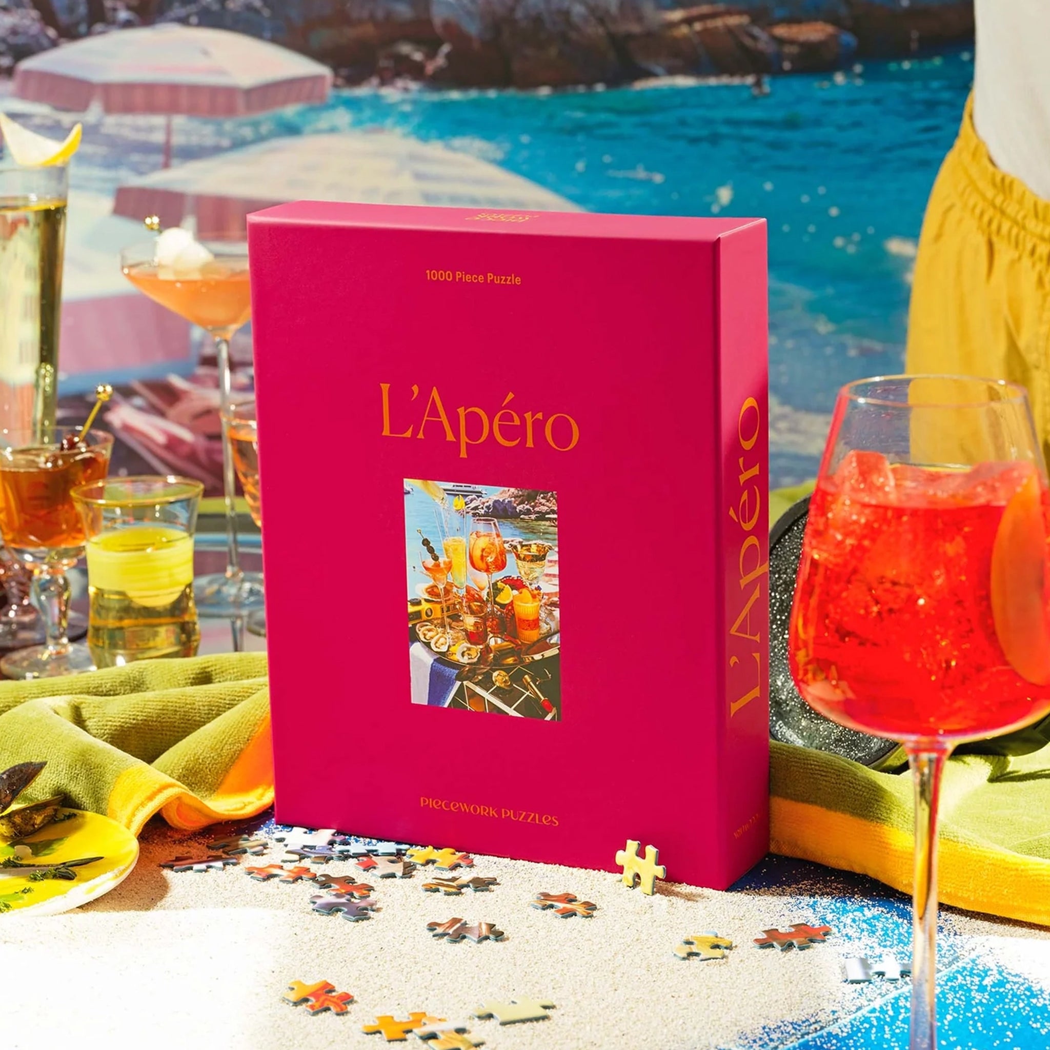 A hot pink puzzle box with an image of a beachside drinks tray with a variety of cocktails and beachside essentials. 