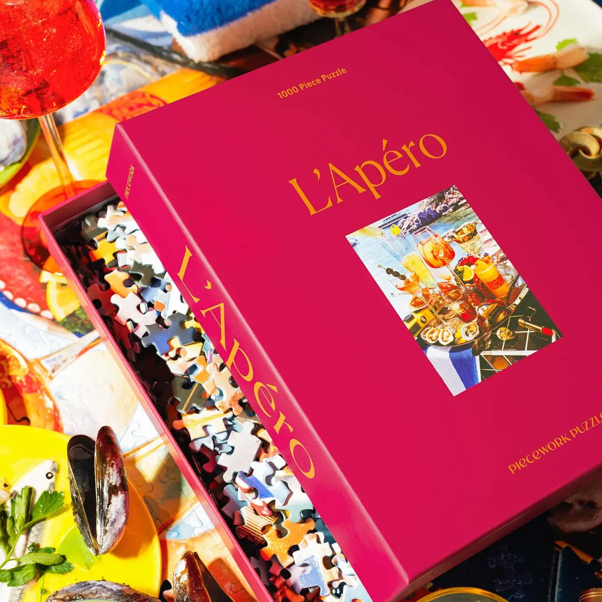 A hot pink puzzle box with an image of a beachside drinks tray with a variety of cocktails and beachside essentials. 