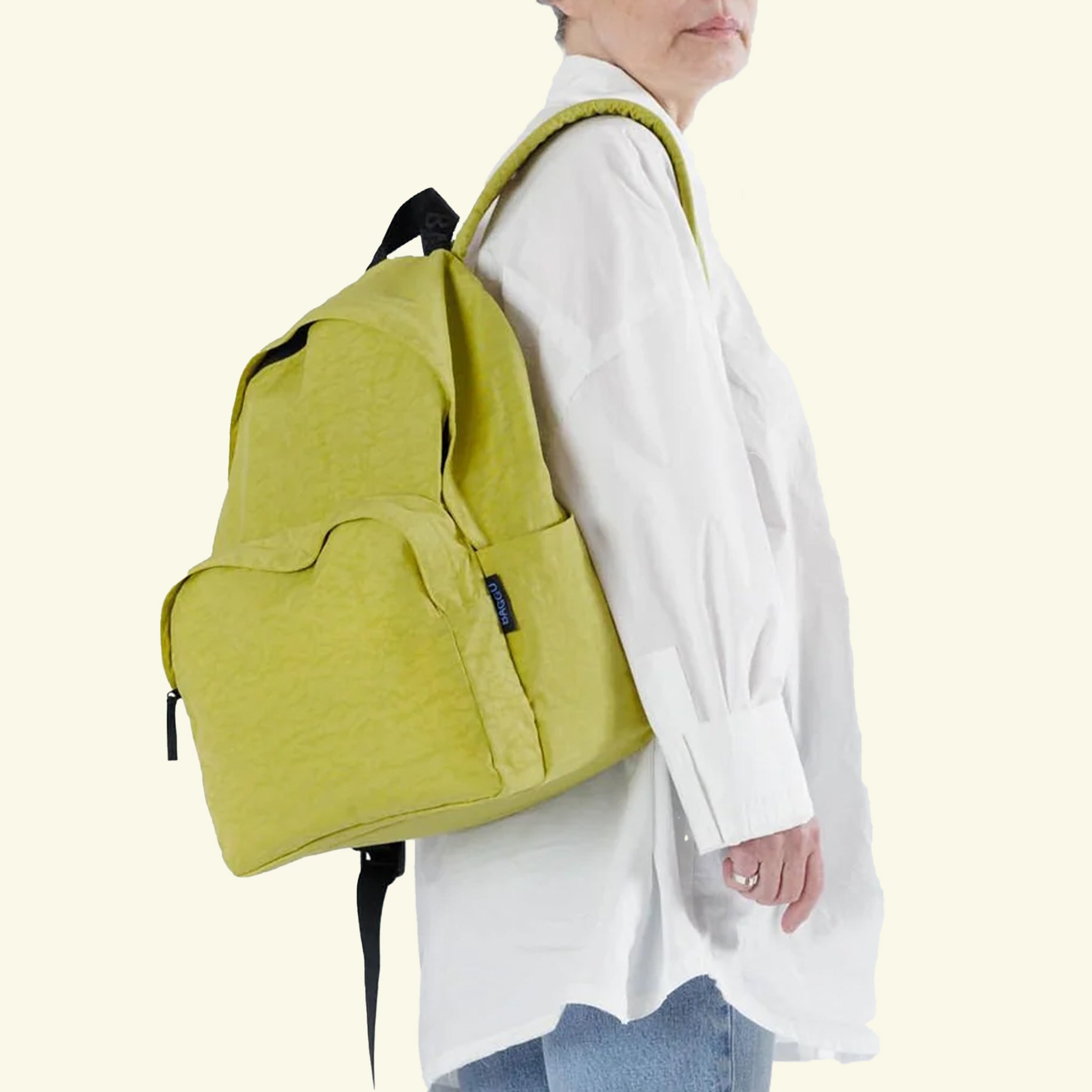 A lemongrass green nylon backpack with front pockets and black details.