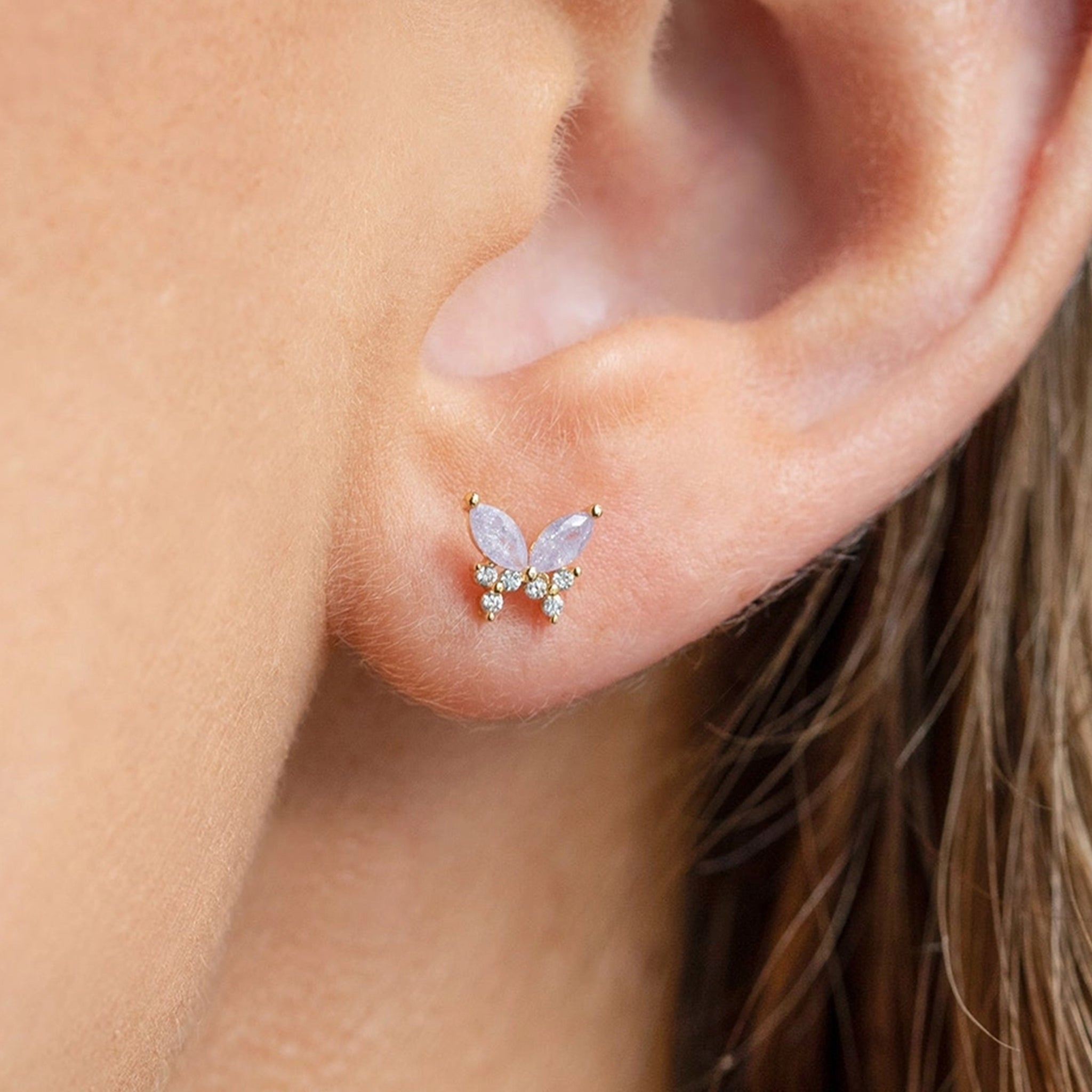 A pair of lavender and clear cz stud earrings in the shape of a butterfly. 