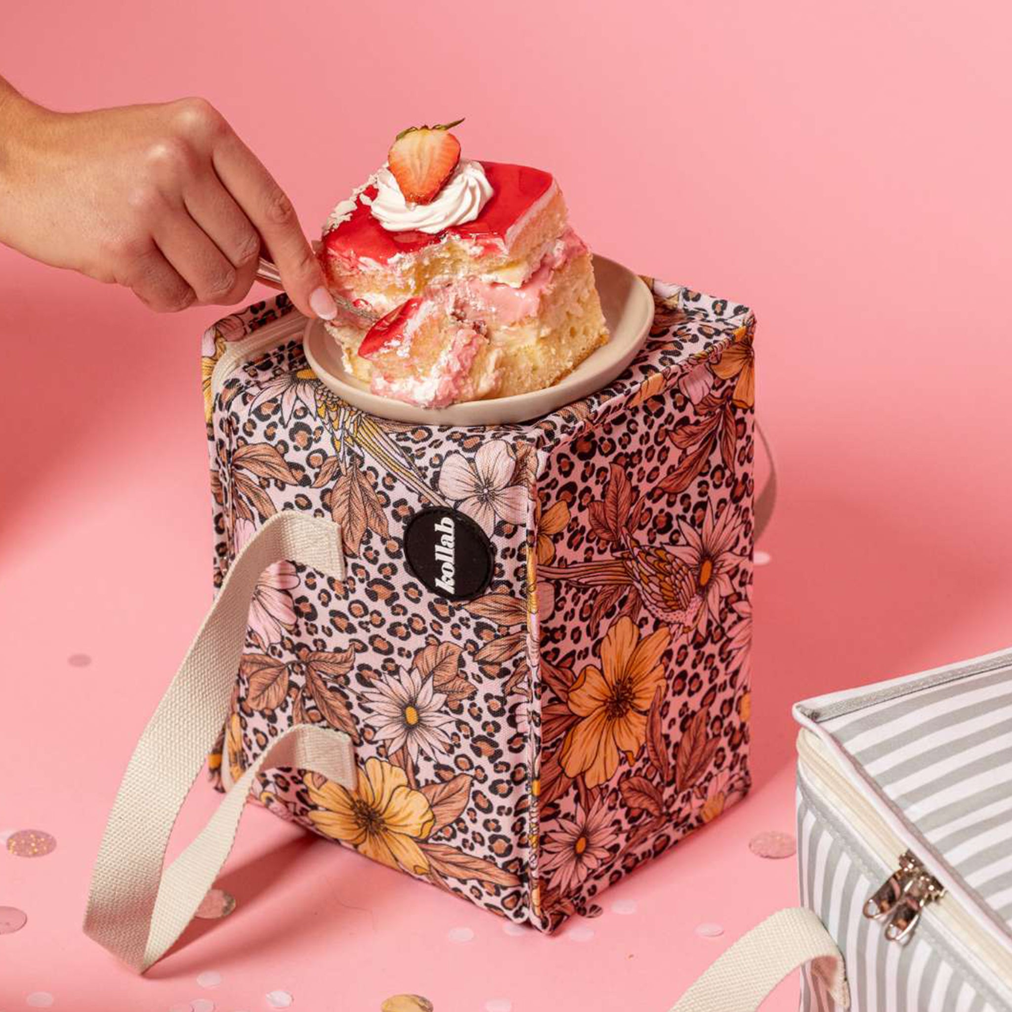 A leopard floral print lunch box with ivory straps. 