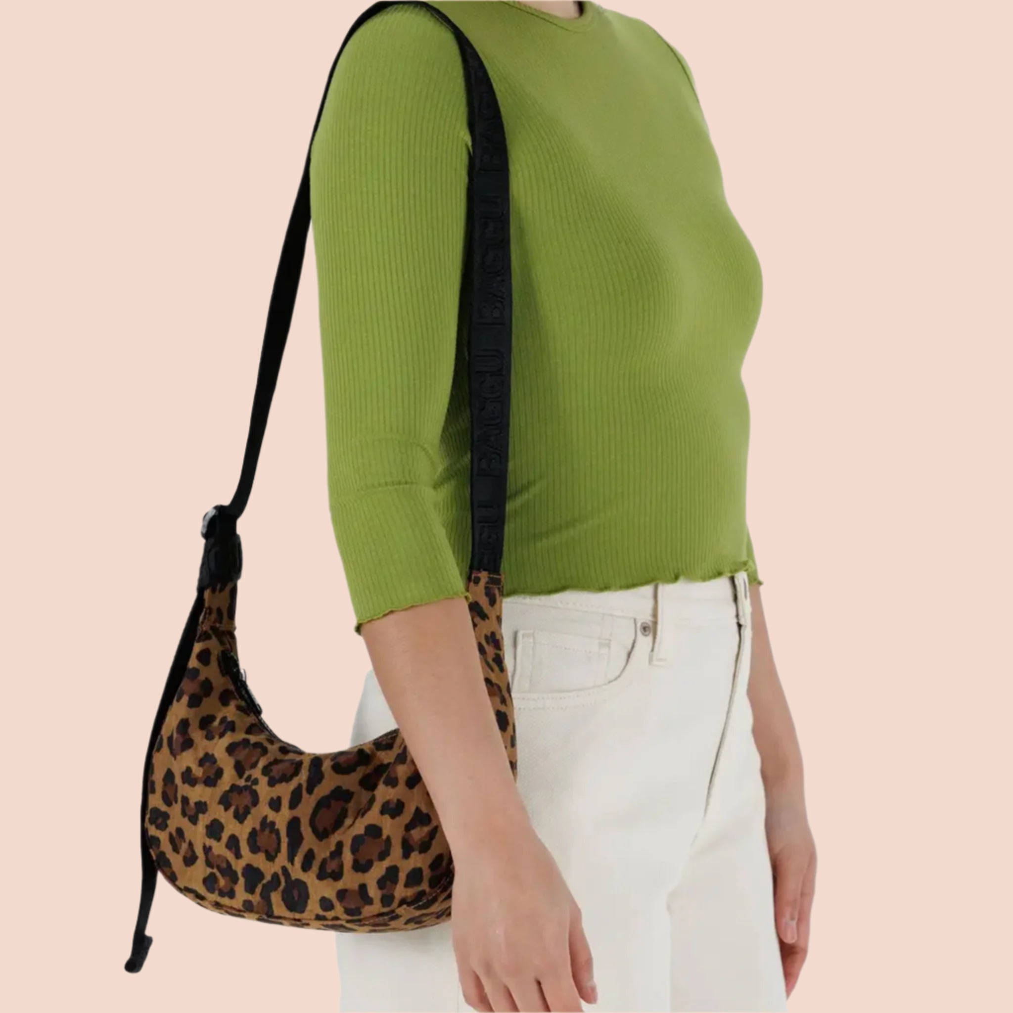 A leopard print curved crescent shaped handbag with a black strap that can adjust from a shoulder bag length to a crossbody. 