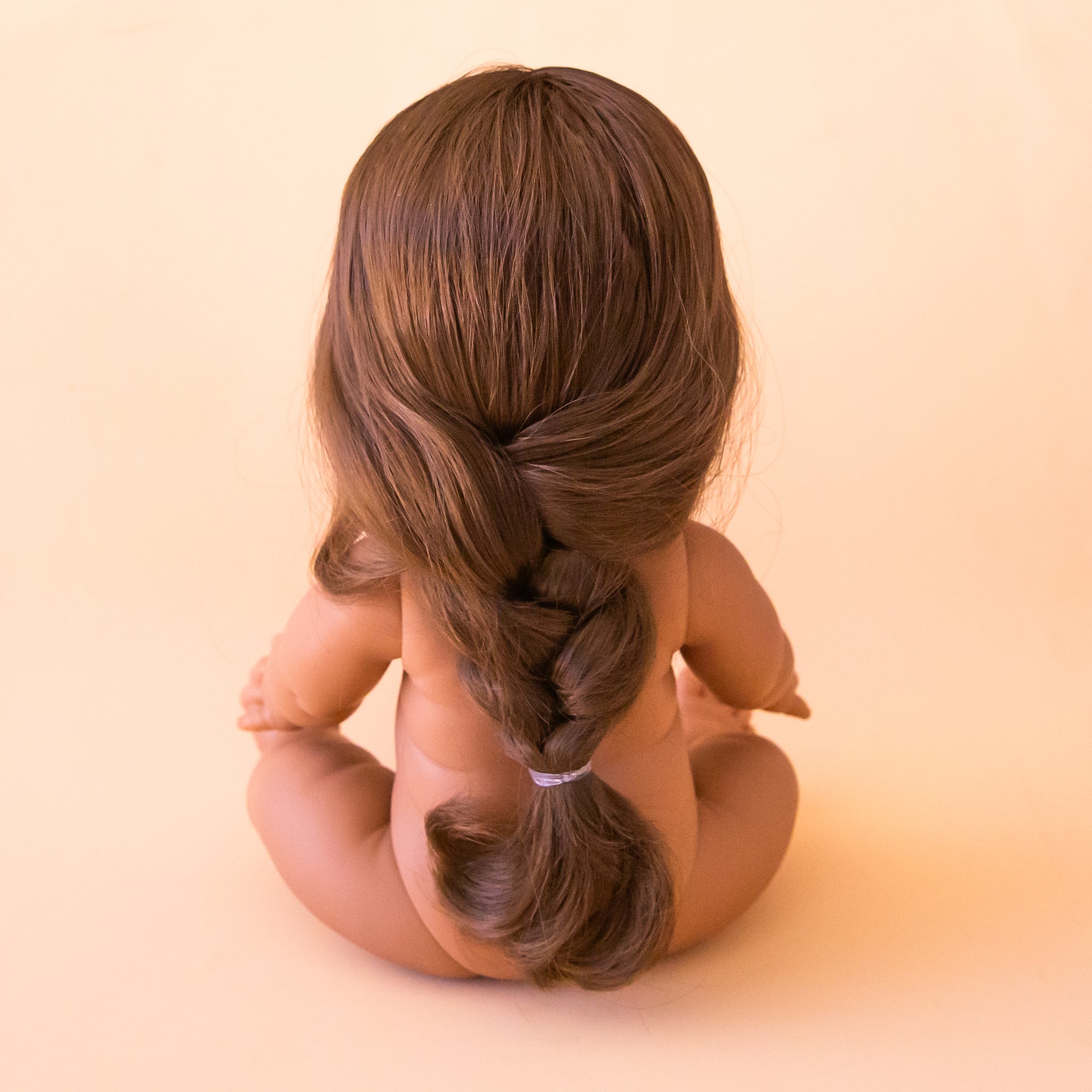 A baby girl doll with brown eyes and brown braided hair. 