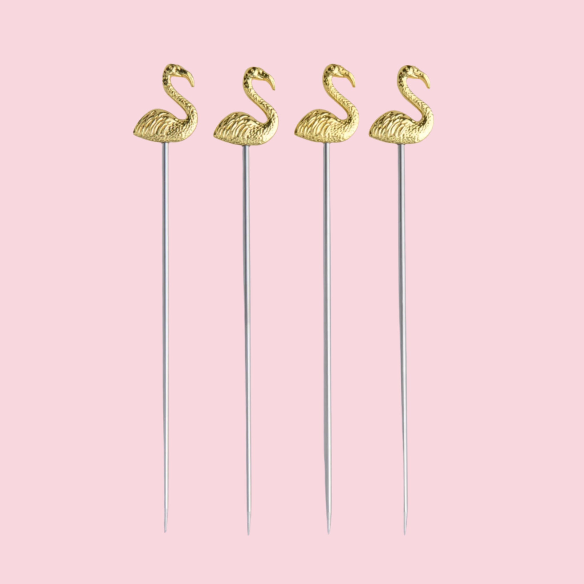 A set of four gold cocktail picks with flamingo shapes at the end. 