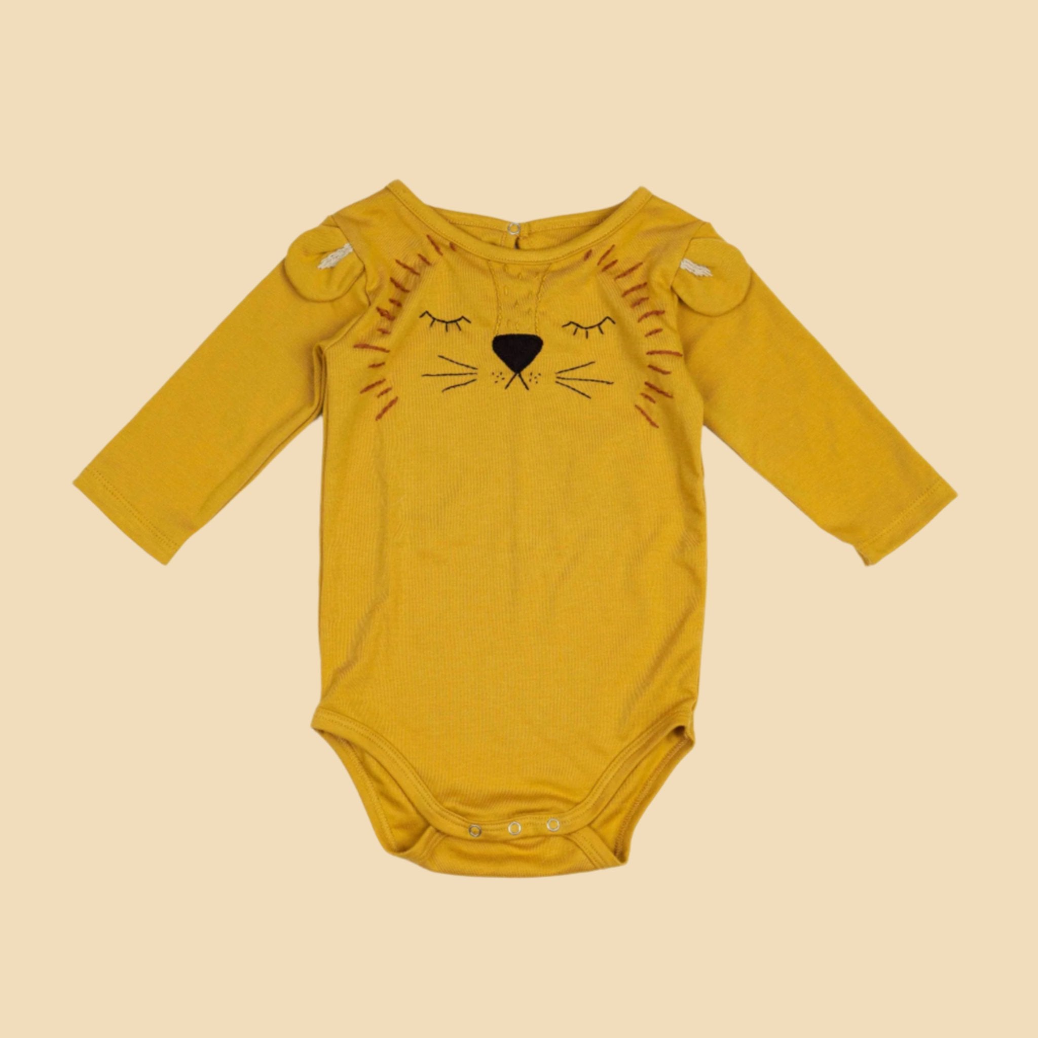 A long sleeve mustard onesie with a lion face in the center. 