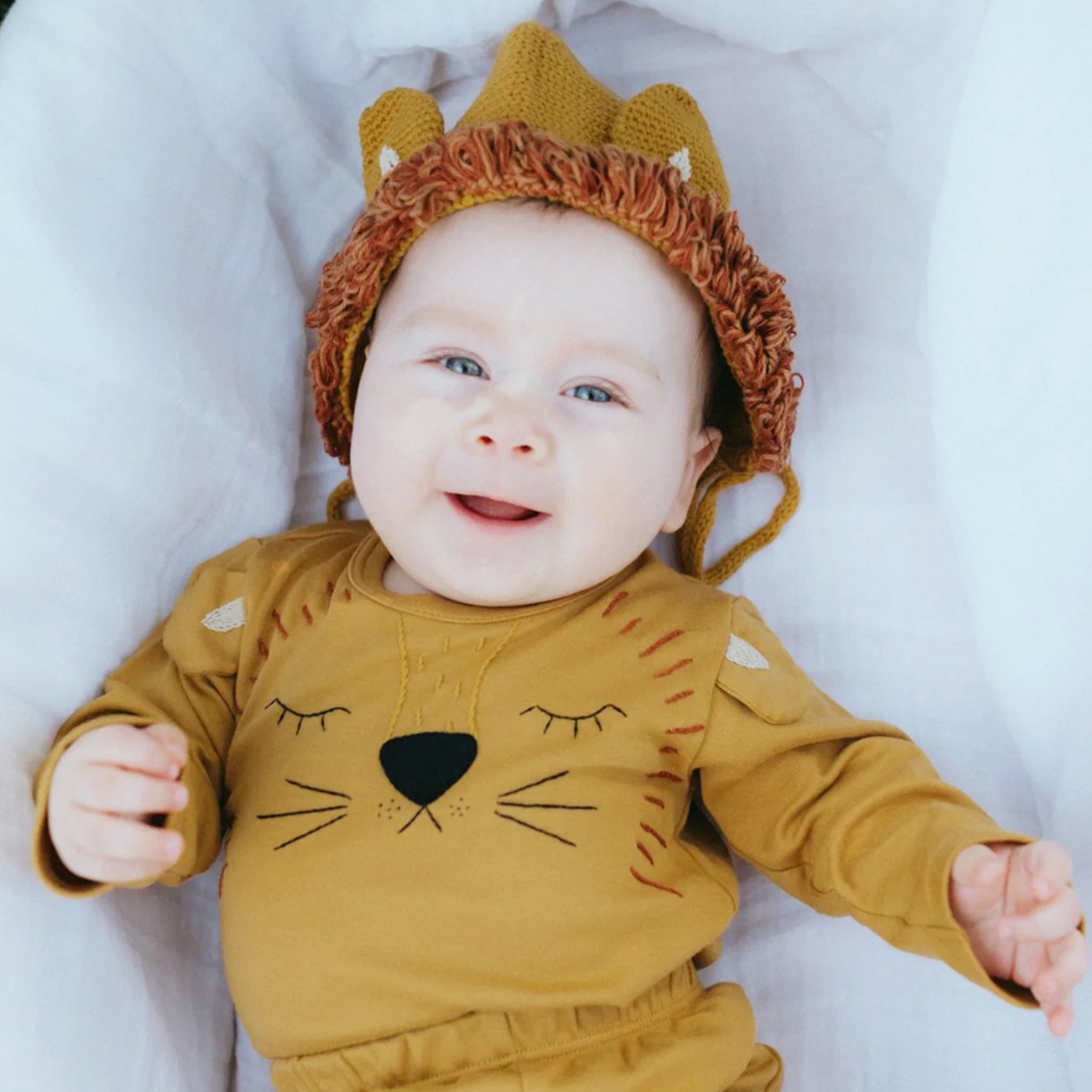 A long sleeve mustard onesie with a lion face in the center. 