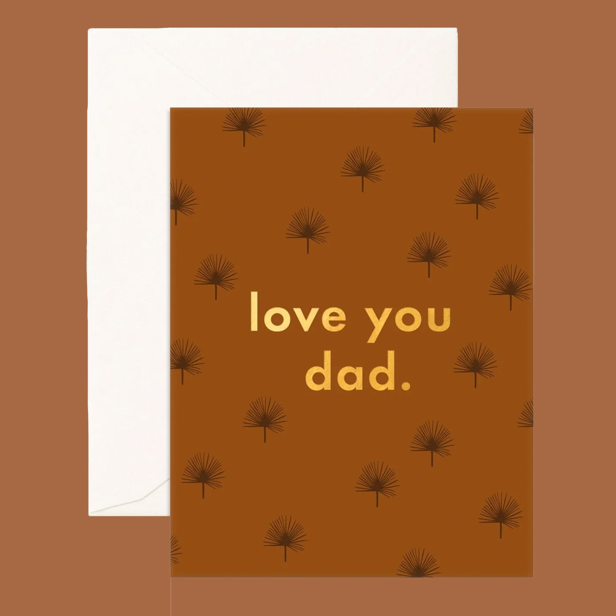 On a brown background is a brown card with gold text that reads, "love you dad." with a palm pattern all over. 