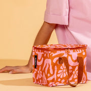 An orange and pink floral print lunch box with faux leather handles.