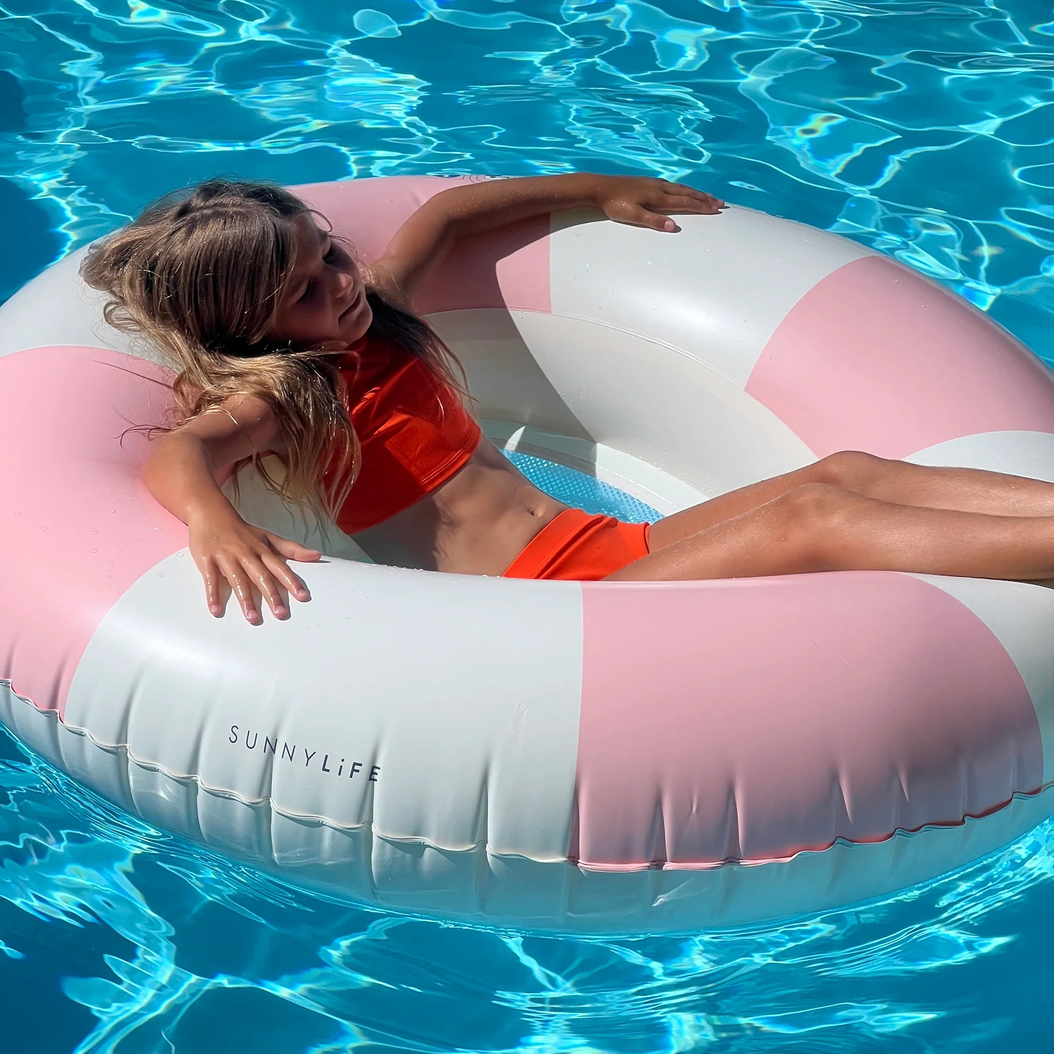 A pink and white striped pool float but the center is in the shape of a heart with a mesh backing. 